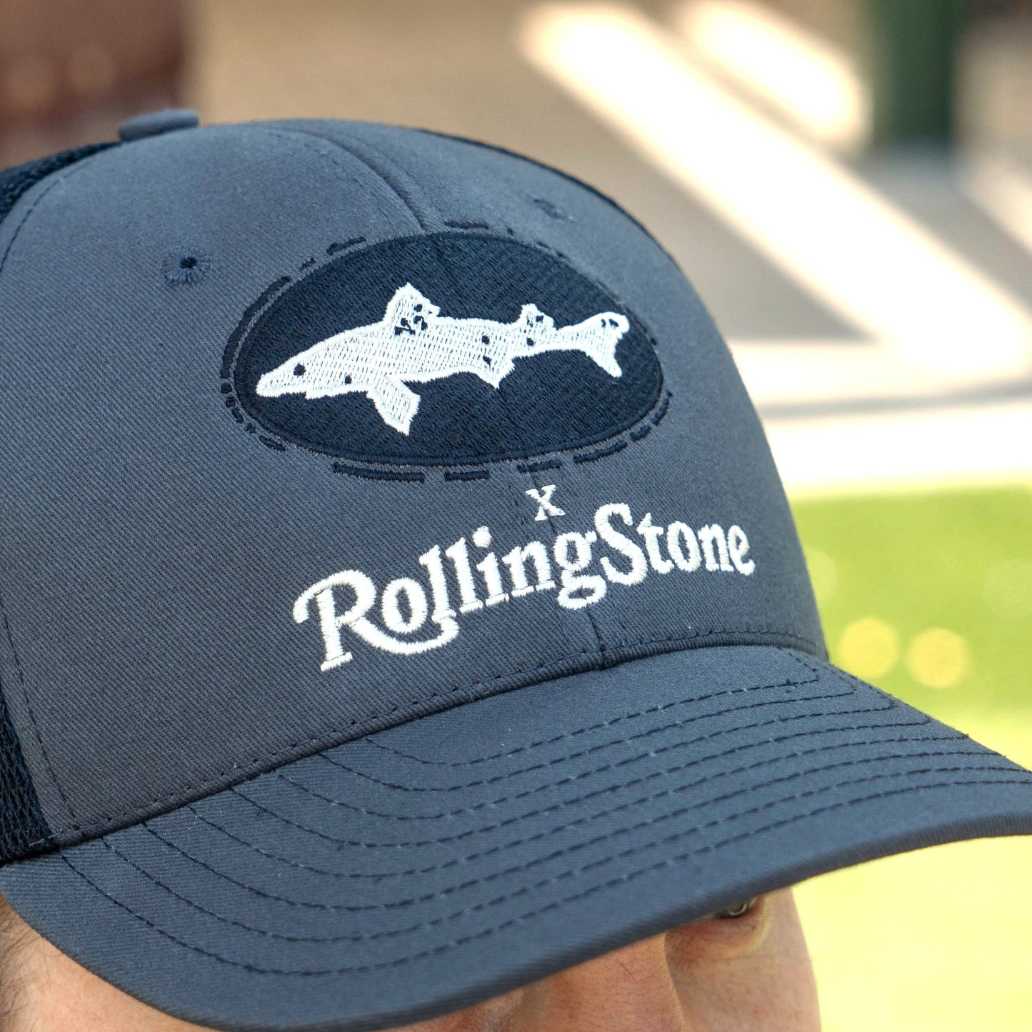 A close-up of the Dogfish Head x Rolling Stone Trucker Hat by Unionwear, featuring a white two-fish graphic and Rolling Stone logo on the front—perfect for fans seeking a distinctive collaboration cap.