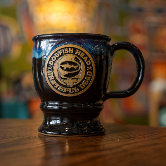 Black and blue ceramic mug with a brown Dogfish Head x Grateful Dead logo.