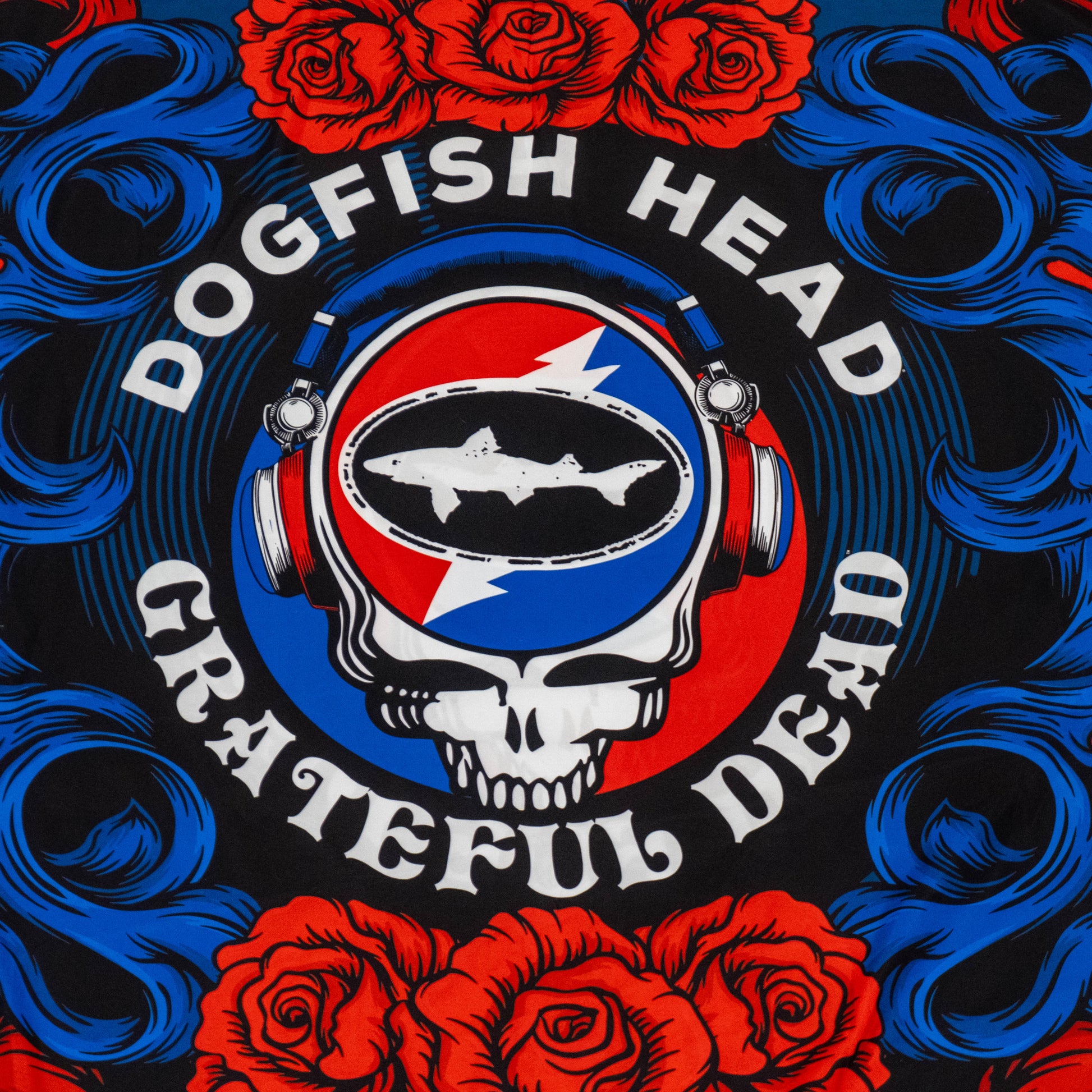 A stylized skull with headphones, a fish logo, and red, white, and blue colors—like a Grateful Dead flag—is surrounded by red roses and swirls. The Merchtank Dogfish Head x Grateful Dead Flag Tapestry captures this craft beer-inspired art.
