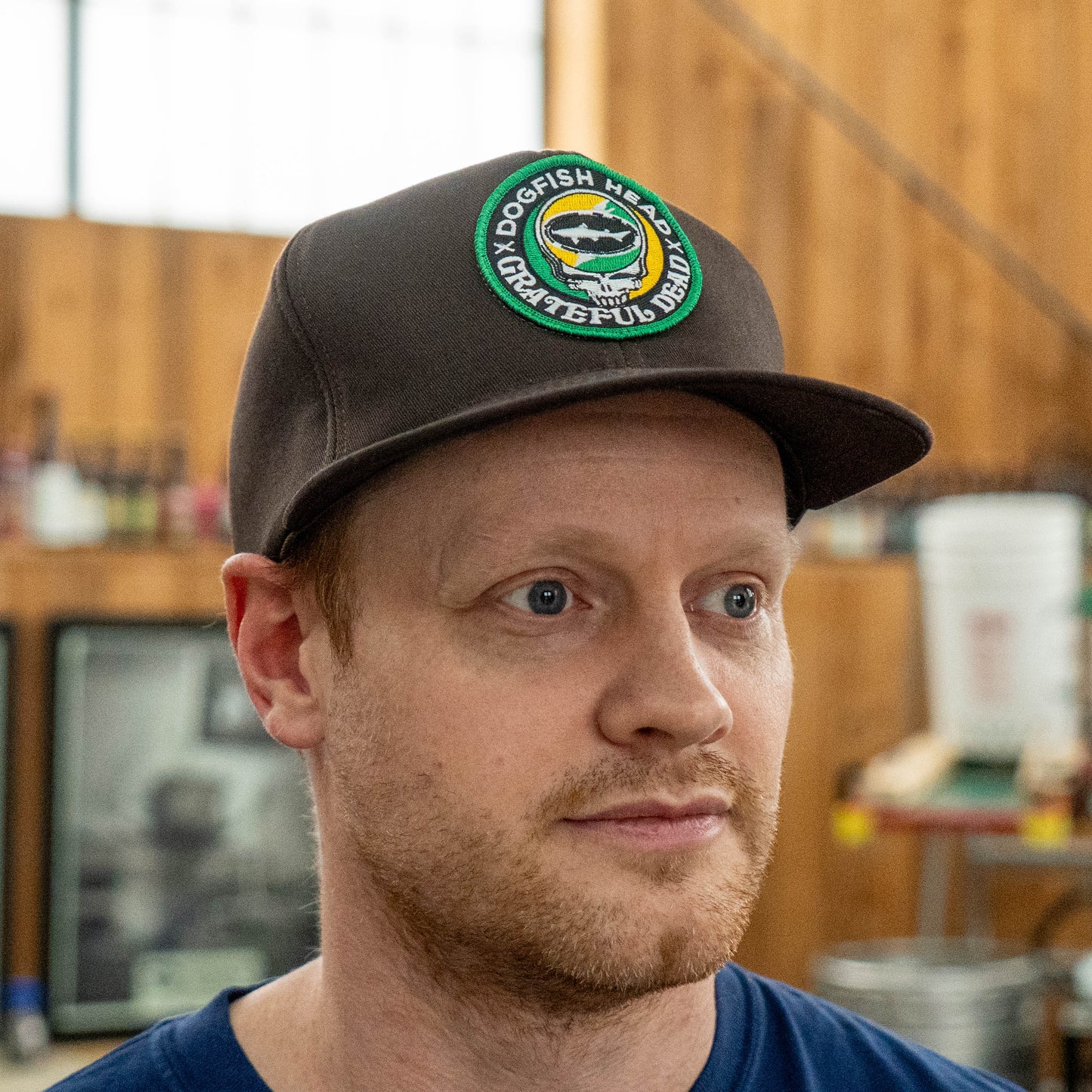 Front view of Dogfish Head x Grateful Dead espresso retro foam baseball hat with green and orange embroidered collaboration logo and flat brim design