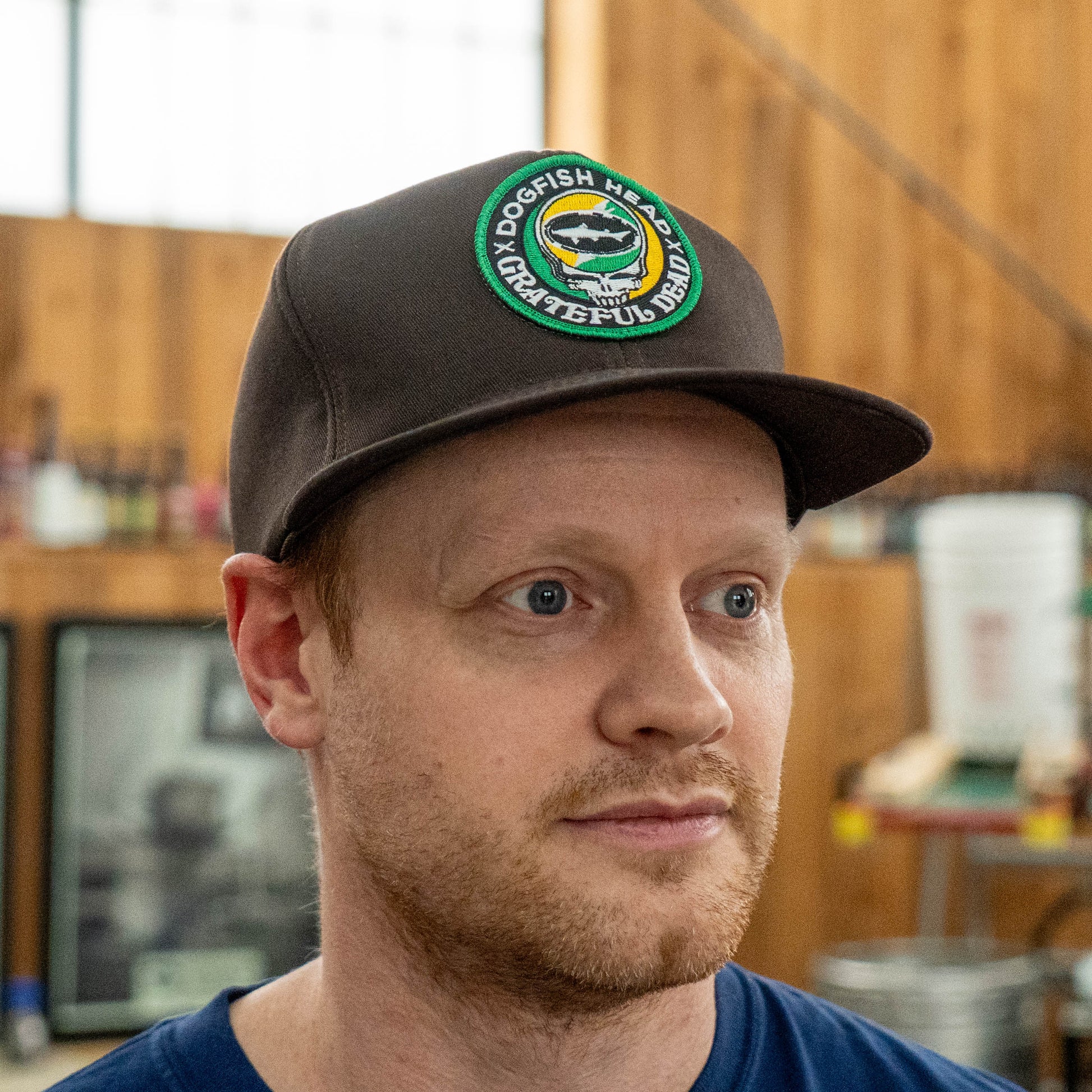Front view of Dogfish Head x Grateful Dead espresso retro foam baseball hat with green and orange embroidered collaboration logo and flat brim design
