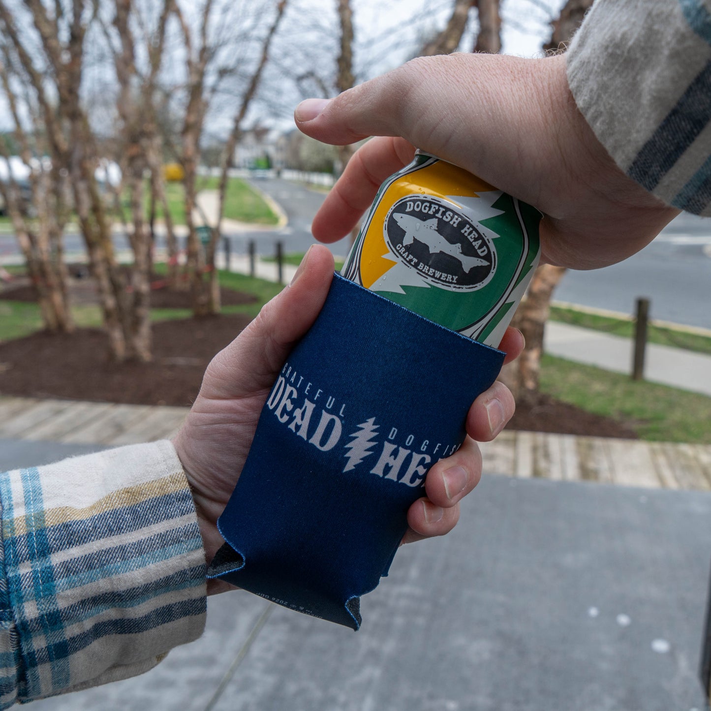 Citrus daydream beer can being inserted into a Dogfish Head x Grateful Dead can cooler, showing stretch neoprene construction and snug fit