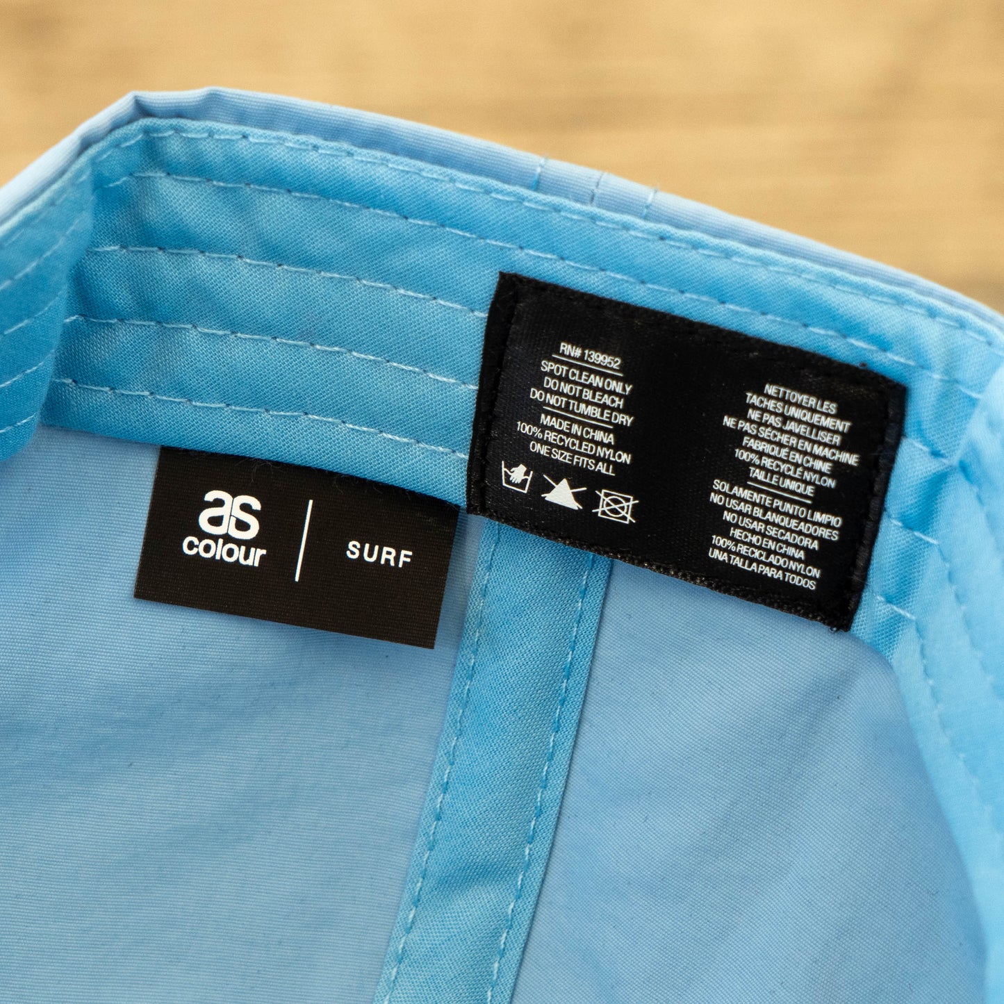 Close-up of the inside label of a Dock Dogs Carolina Blue Surf Hat by GO WEST T-SHIRT COMPANY, featuring branding and care instructions stitched into the recycled nylon fabric.