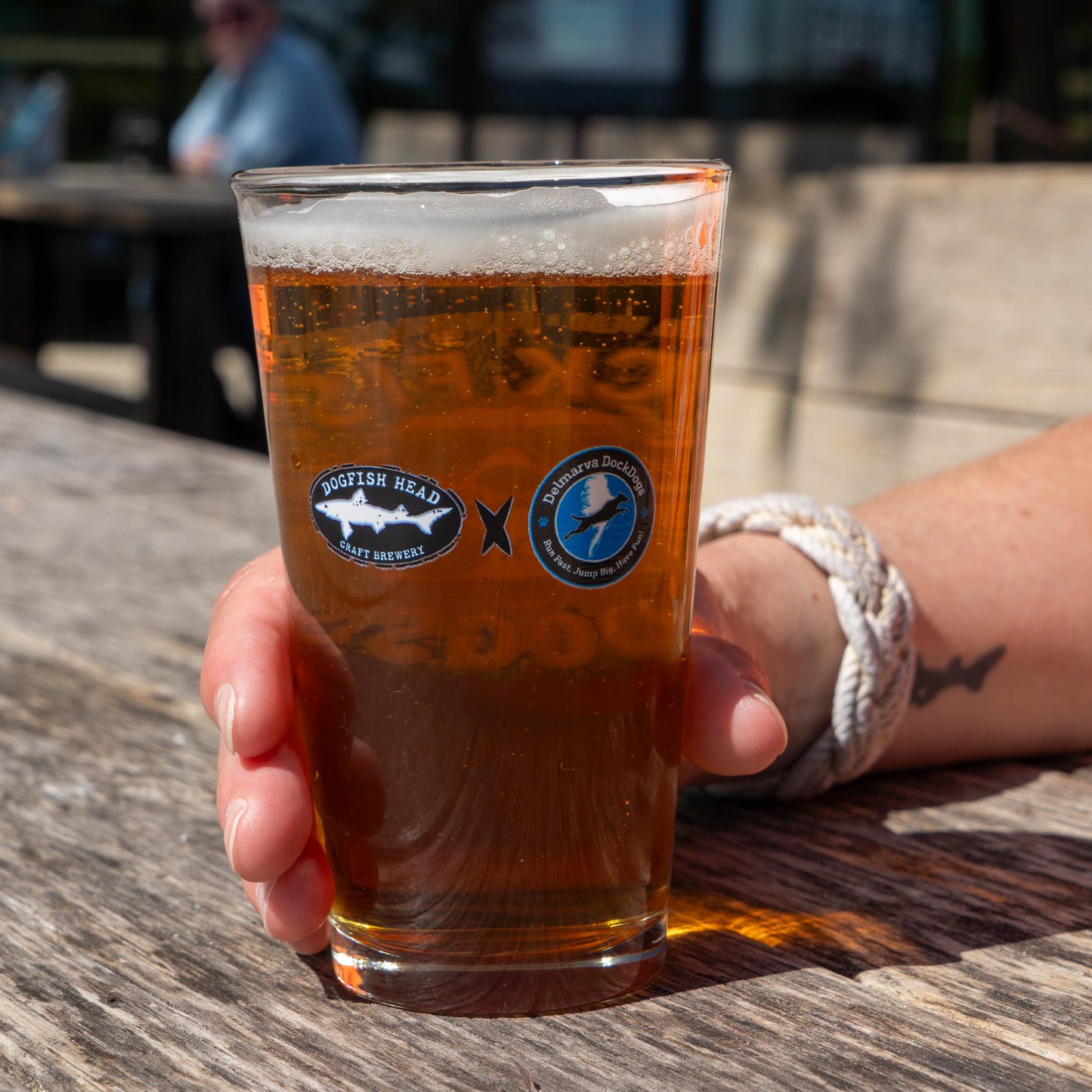 Classic black Dogfish Head logo and a Delmarva DockDogs logo on a pint glass filled with beer