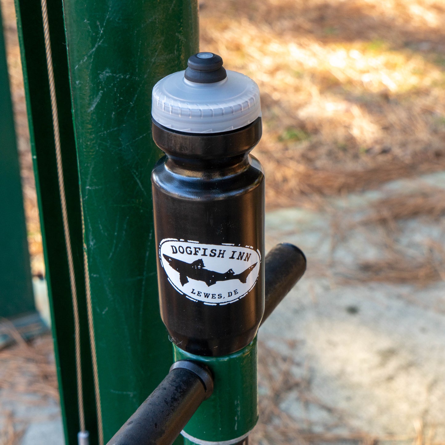 Dogfish Inn branded water bottle on a handlebar with a blurred natural background