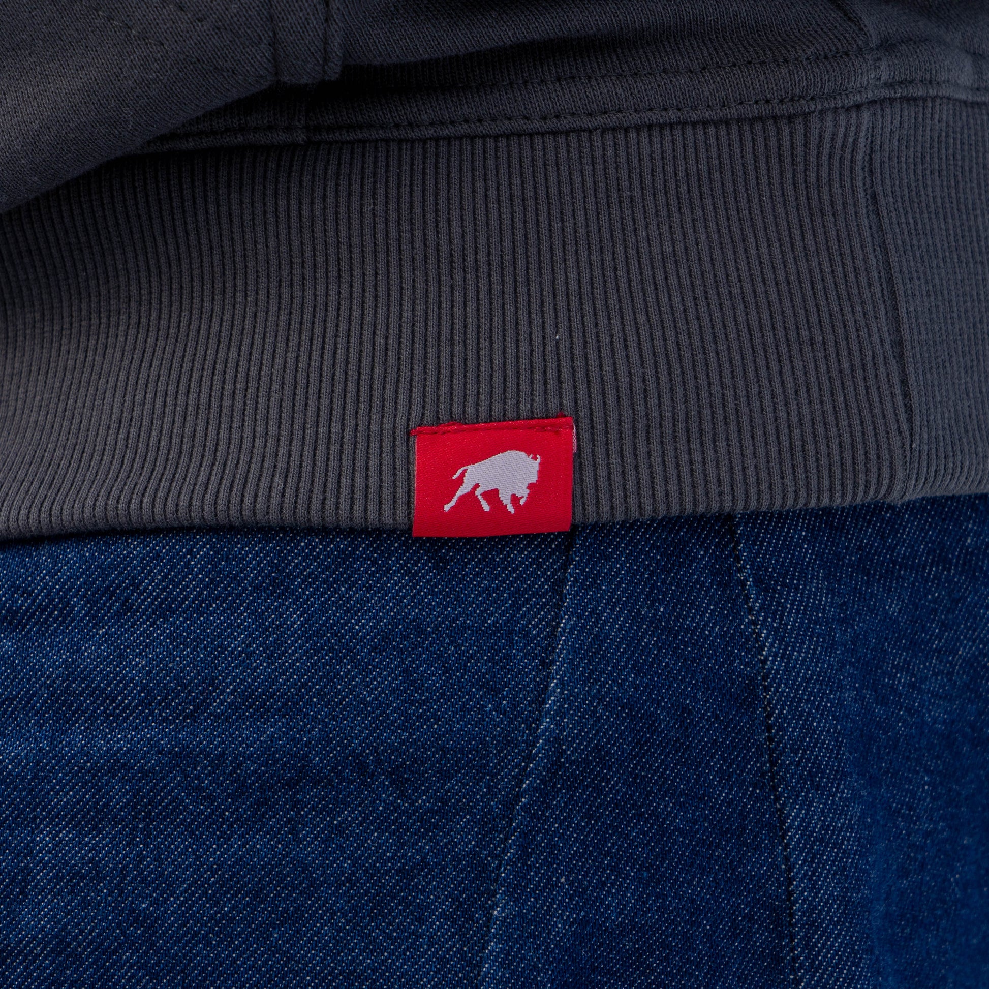 Close up of red Sportiqe tag on the hemline of the Onyx Delaware Hoodie.