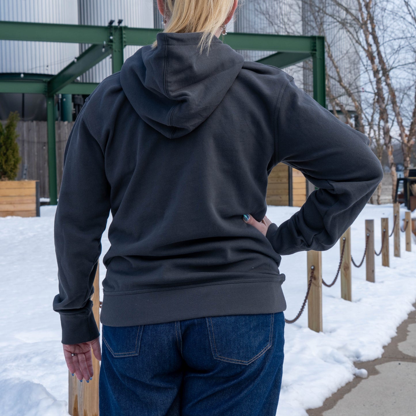Back view of a woman posing with a hand on her hip, wearing an onyx delaware hoodie
