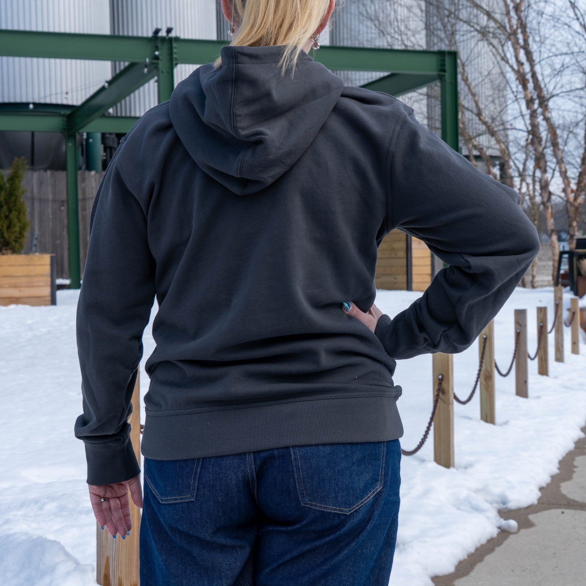 Back view of a woman posing with a hand on her hip, wearing an onyx delaware hoodie