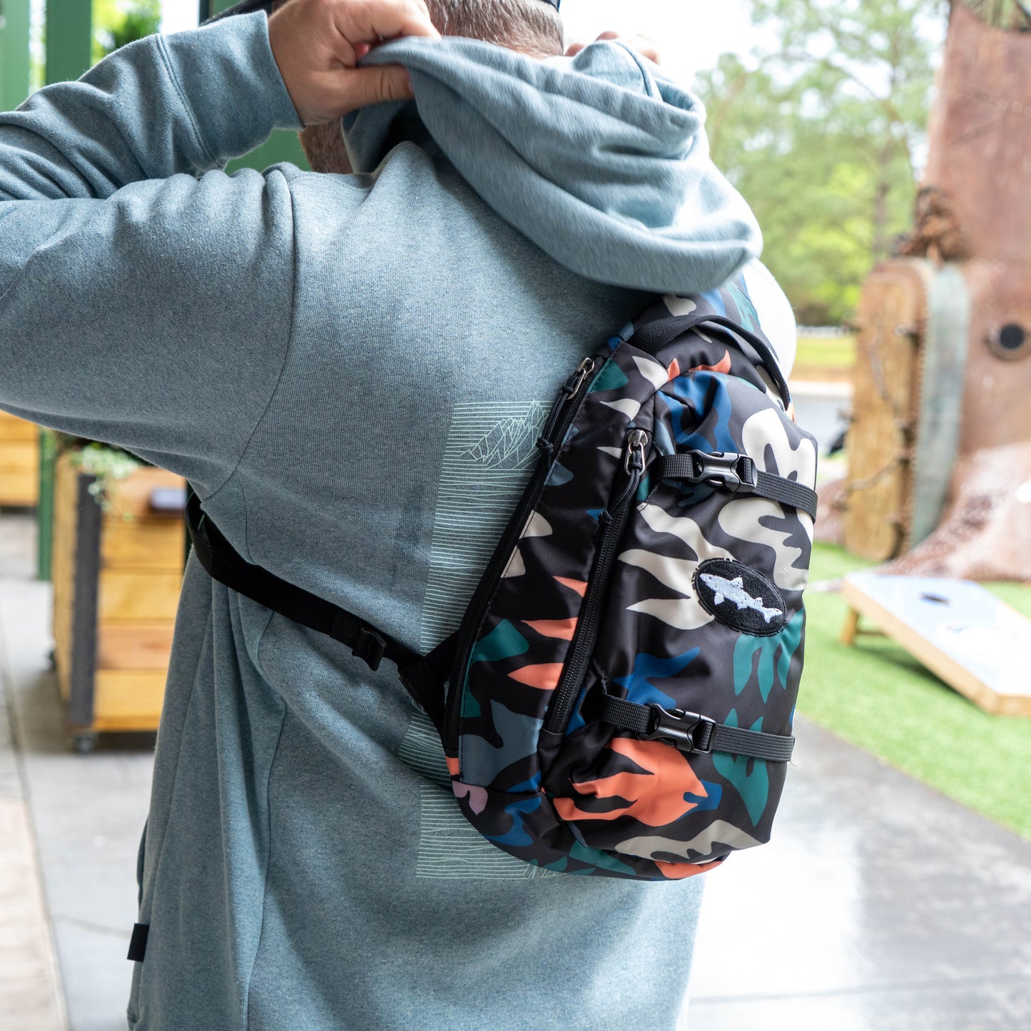 Patagonia Black Atom Sling 8L crossbody sling bag in camo print worn outdoors, lightweight everyday carry bag for travel and hiking