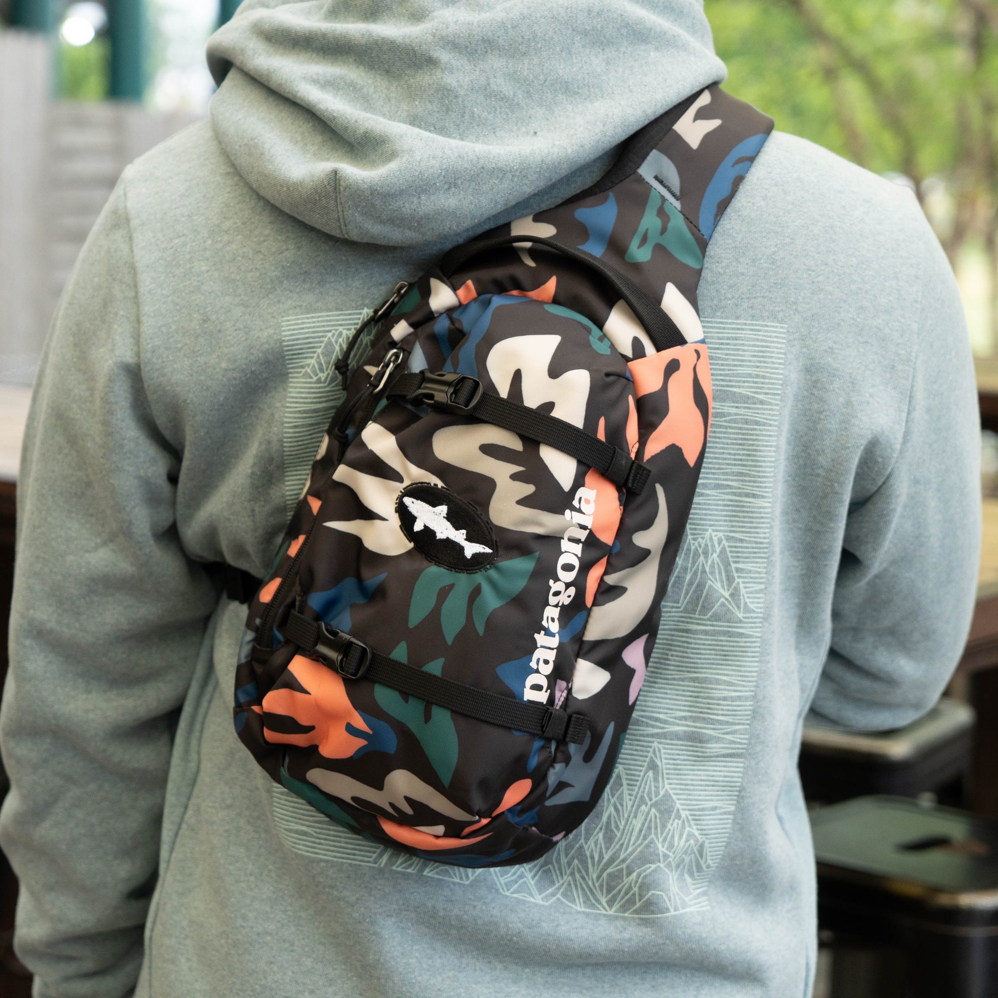 Close-up of Patagonia Black Atom Sling 8L camo sling backpack with adjustable strap and zipper pockets, ergonomic crossbody design
