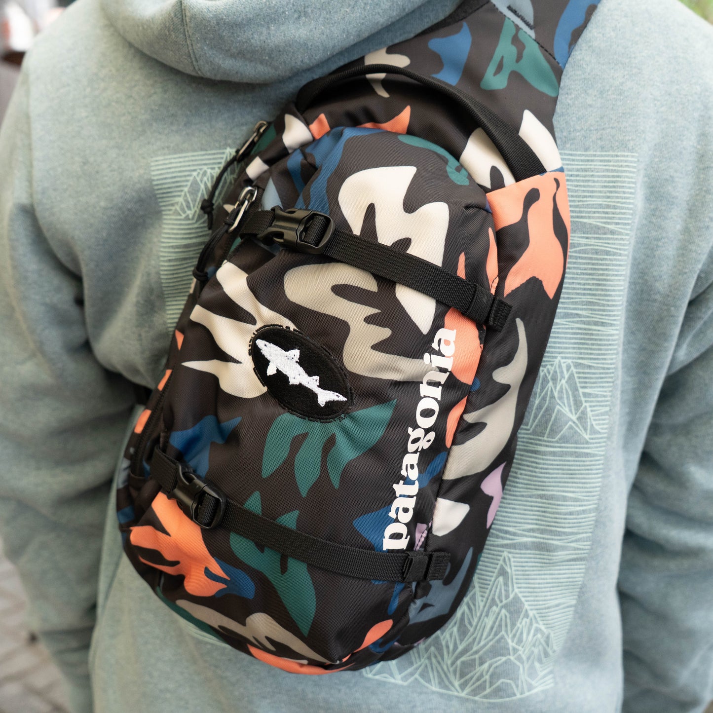 Patagonia Atom Sling 8L camo crossbody bag with adjustable chest strap and buckle detail, lightweight everyday carry for travel and outdoor use
