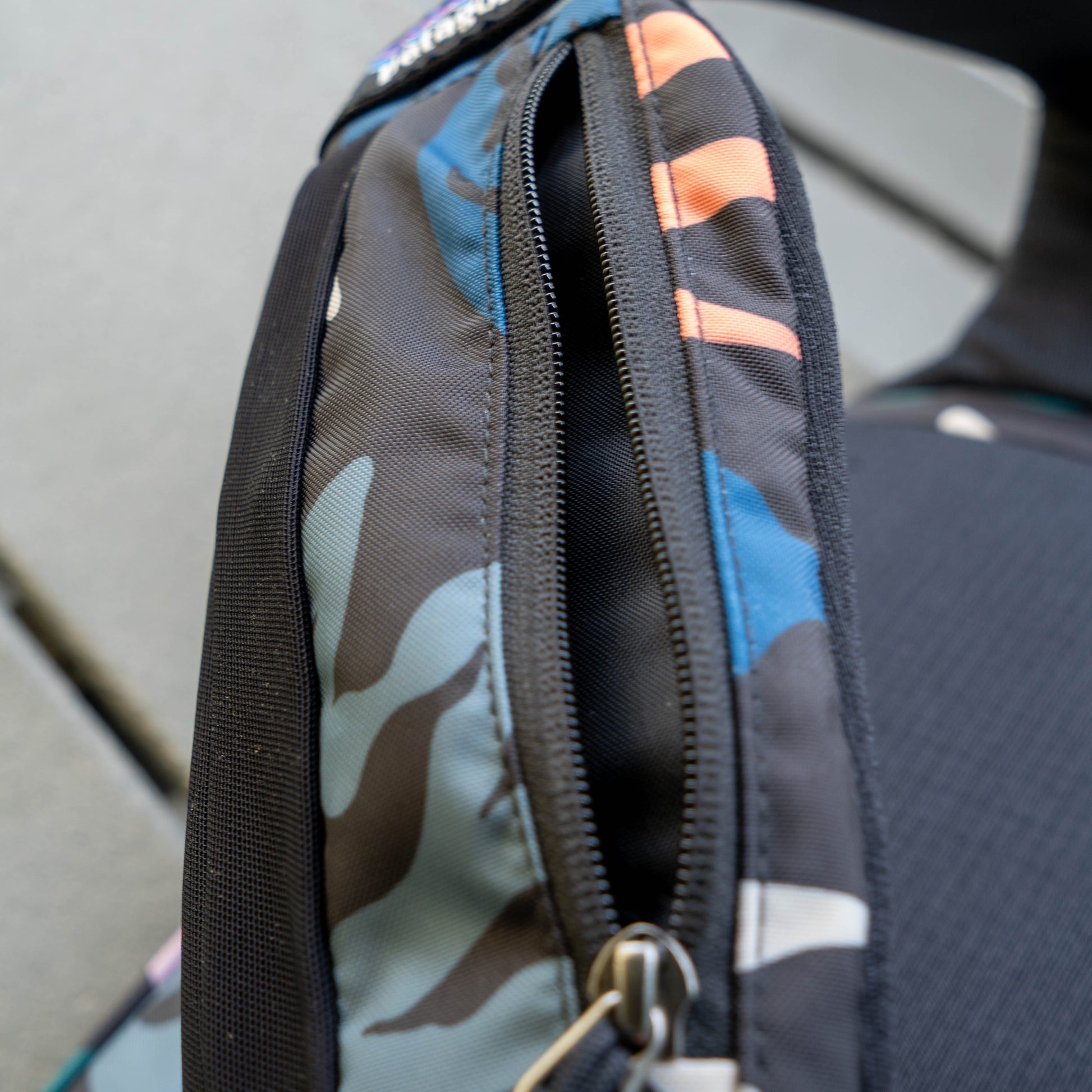 Detailed zipper and seam construction on Patagonia Atom Sling 8L camo sling bag, durable outdoor backpack hardware and stitching