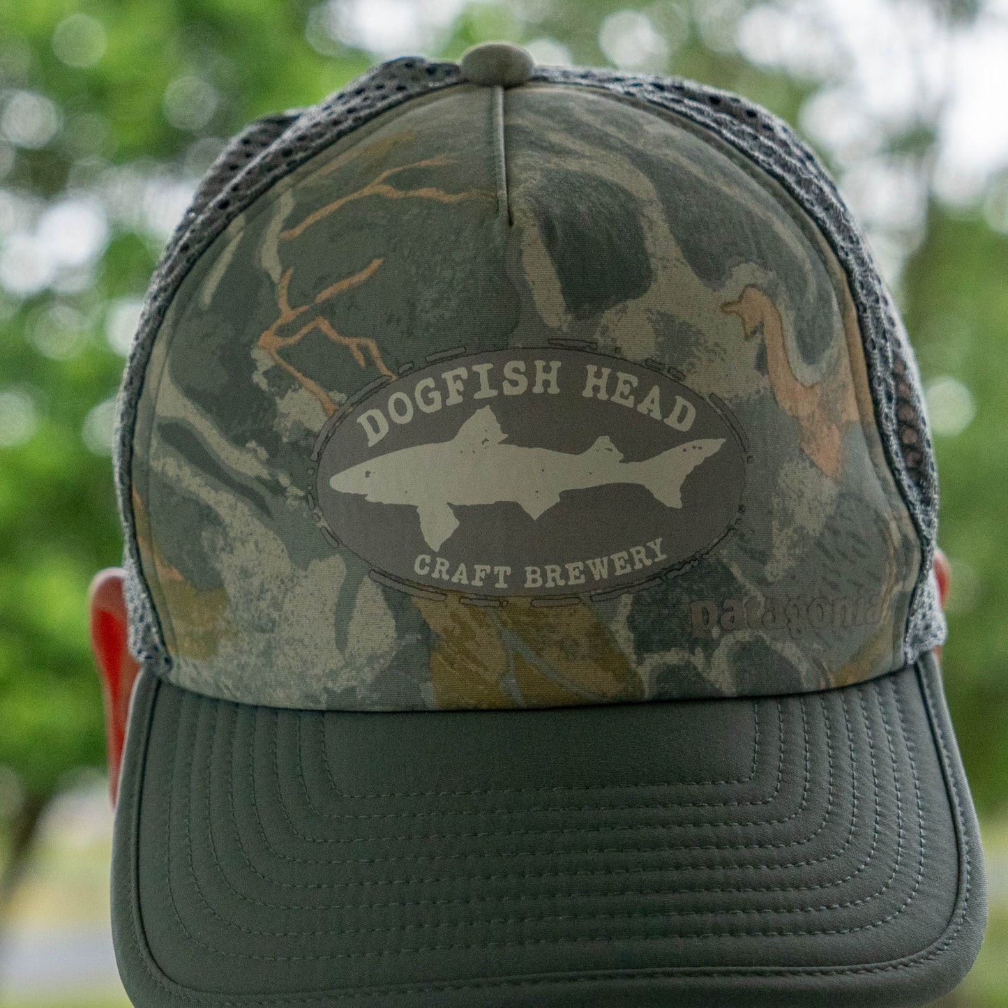 Camouflage Patagonia trucker hat featuring Dogfish Head Craft Brewery shark emblem