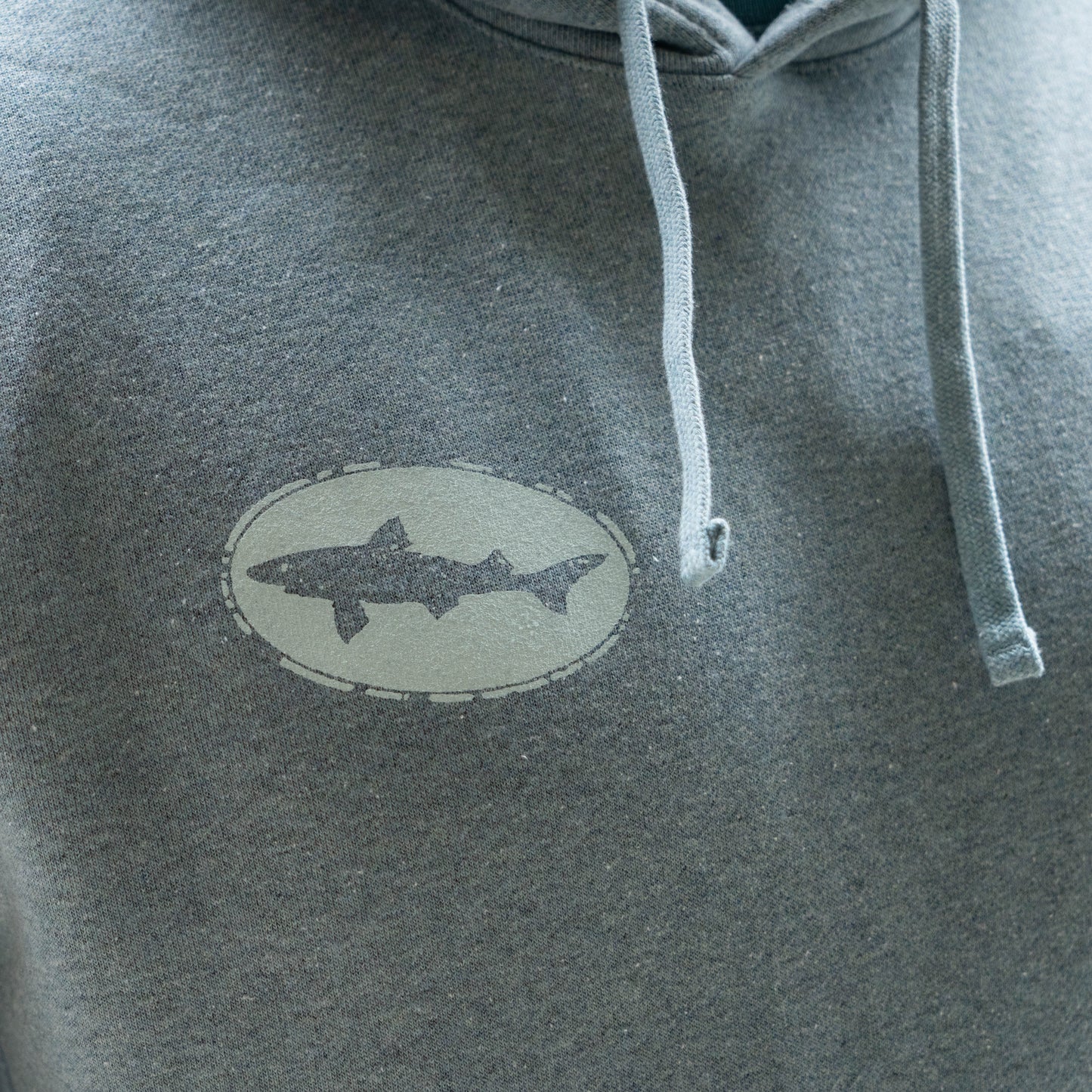Detailed view of Patagonia Strataspire Uprisal grey hoodie with drawstrings and stitched fish logo patch on textured fleece material