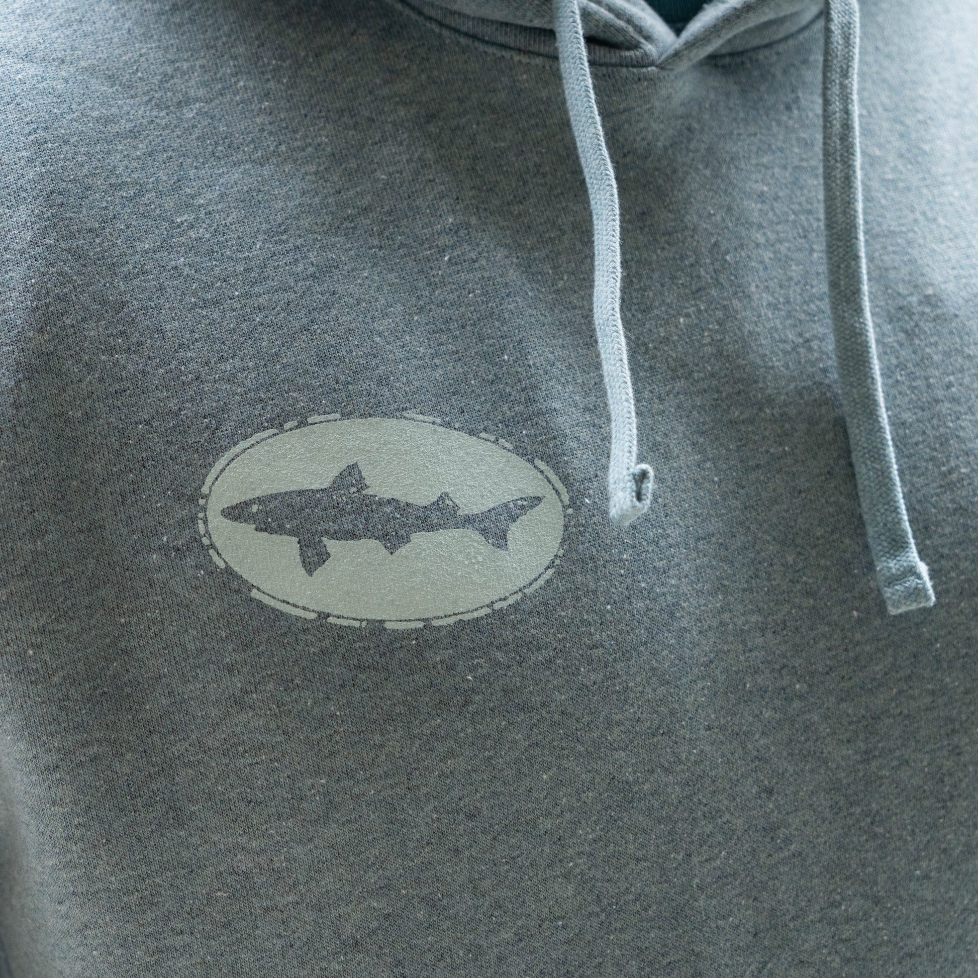Detailed view of Patagonia Strataspire Uprisal grey hoodie with drawstrings and stitched fish logo patch on textured fleece material