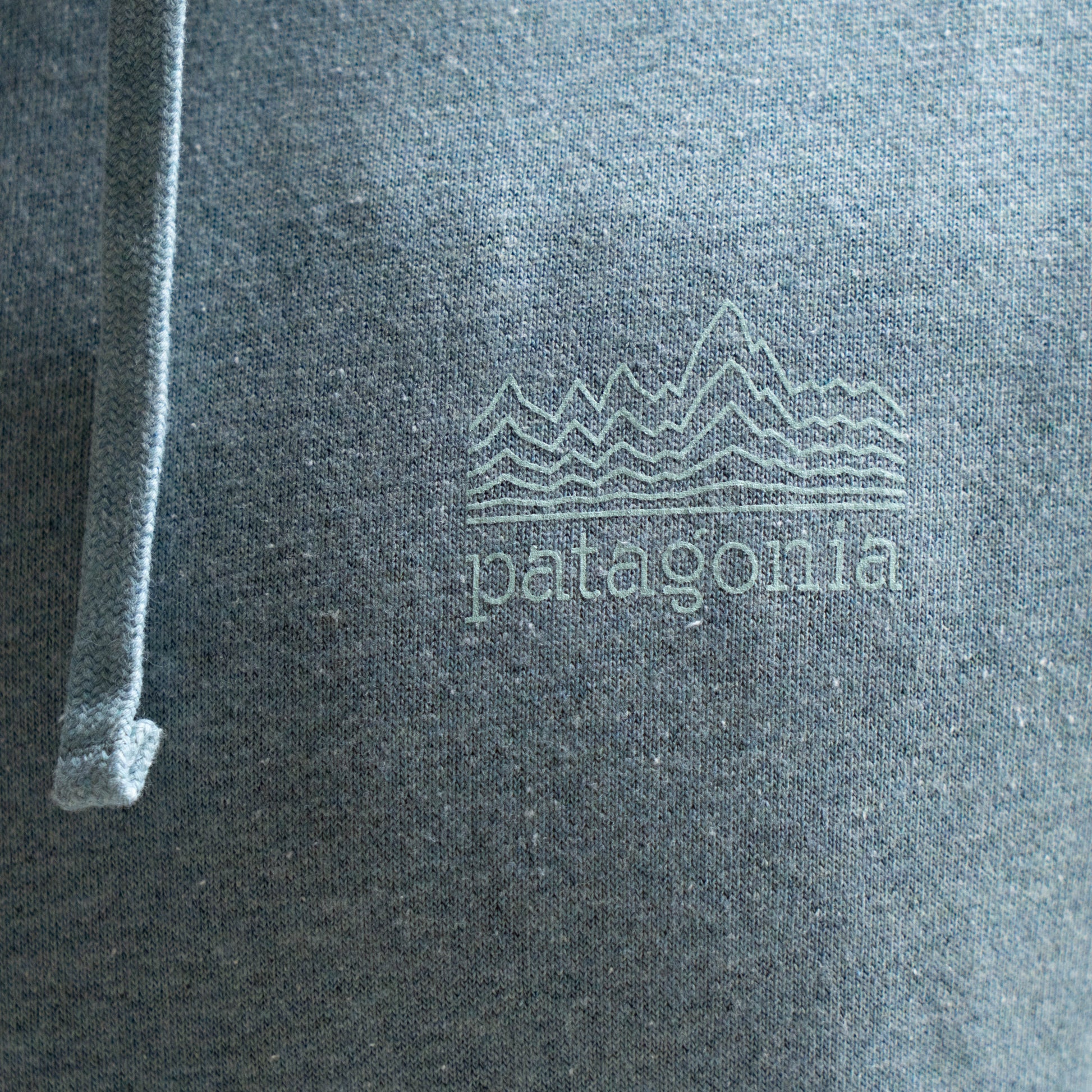 Close-up of Patagonia logo on grey heather hoodie with subtle mountain graphic print