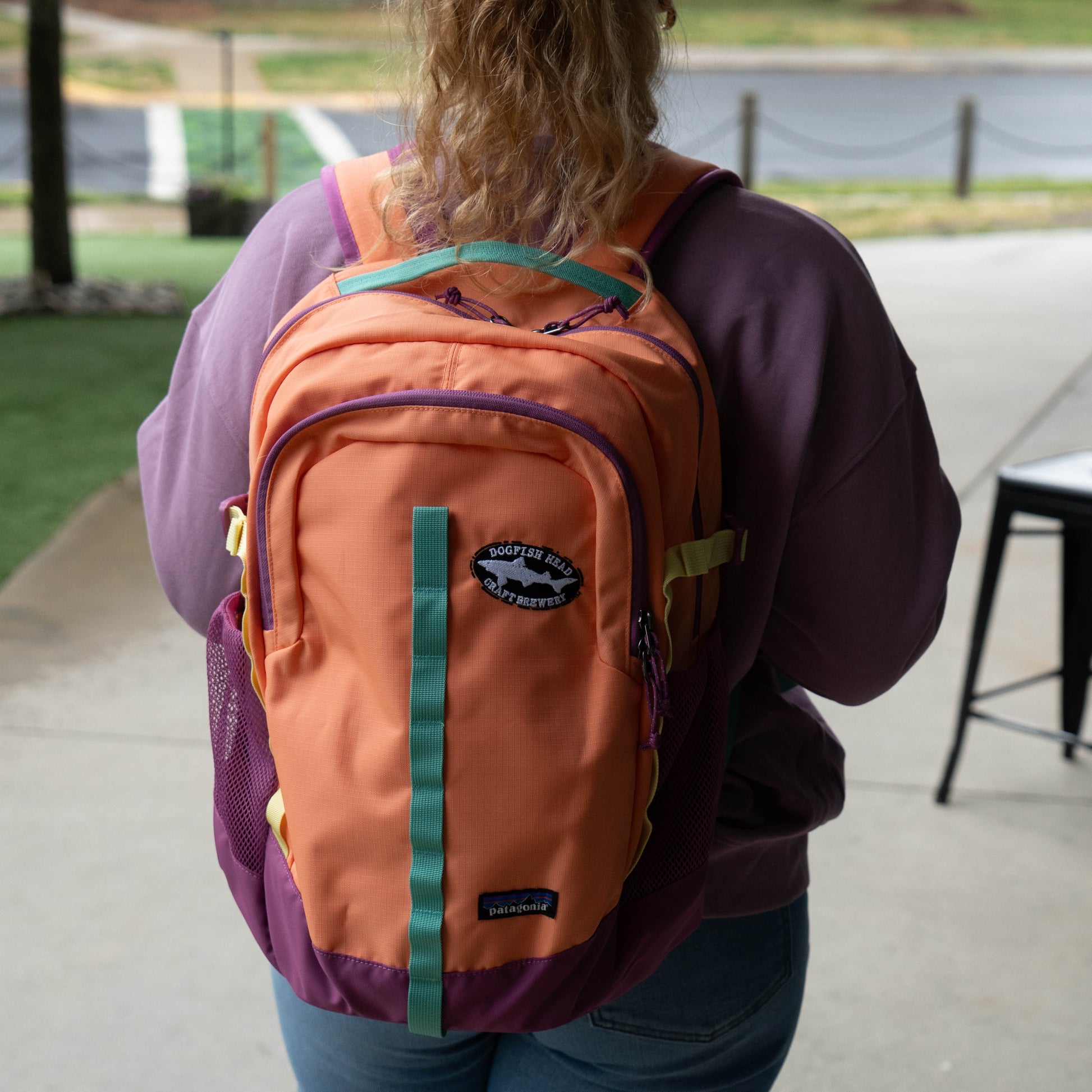 Patagonia Refugio 26L daypack in coral and purple worn outdoors, featuring front pocket, durable recycled fabric, and casual everyday carry design