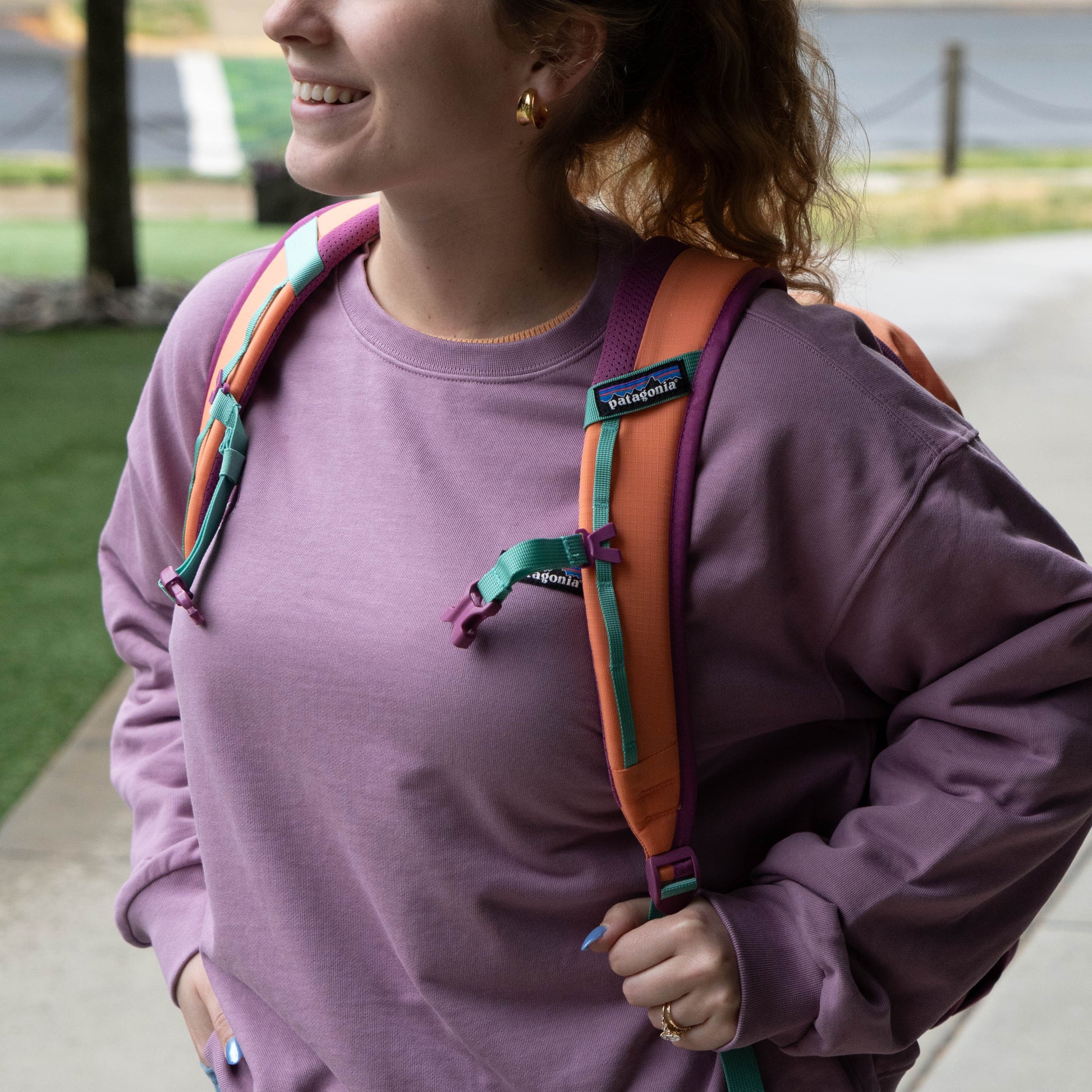 Patagonia Refugio 26L backpack shoulder straps and sternum strap detail in coral, purple, and teal, highlighting adjustable fit for hiking and commuting comfort