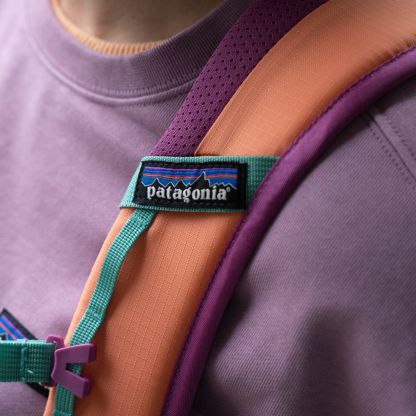 Close-up of Patagonia logo patch on Refugio 26L backpack with breathable purple mesh shoulder strap and durable ripstop fabric detail