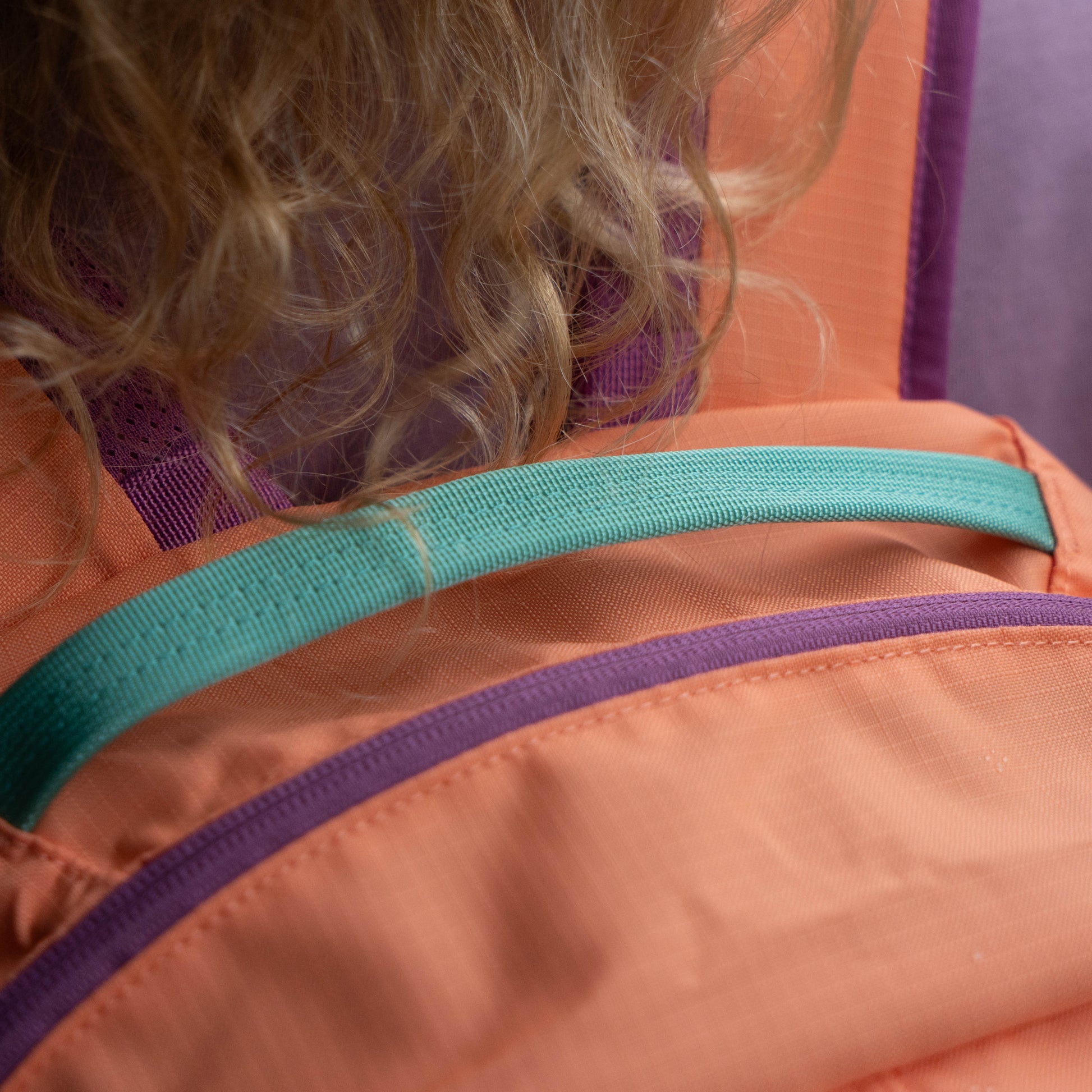 Patagonia Refugio 26L backpack top handle and shoulder strap detail in coral and teal, highlighting durable webbing and comfortable carry design