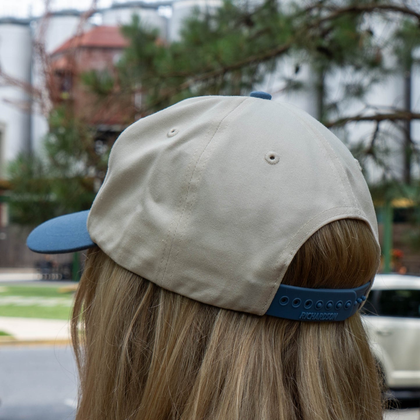 Person wearing a beige and blue cap outdoors with blurred background