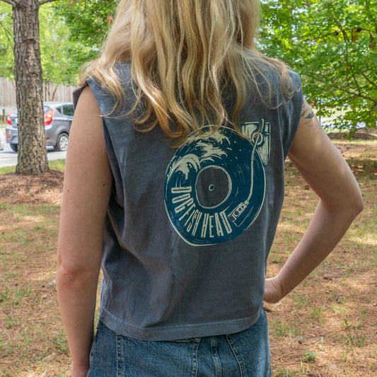 Person wearing a sleeveless denim shirt with a graphic design outdoors