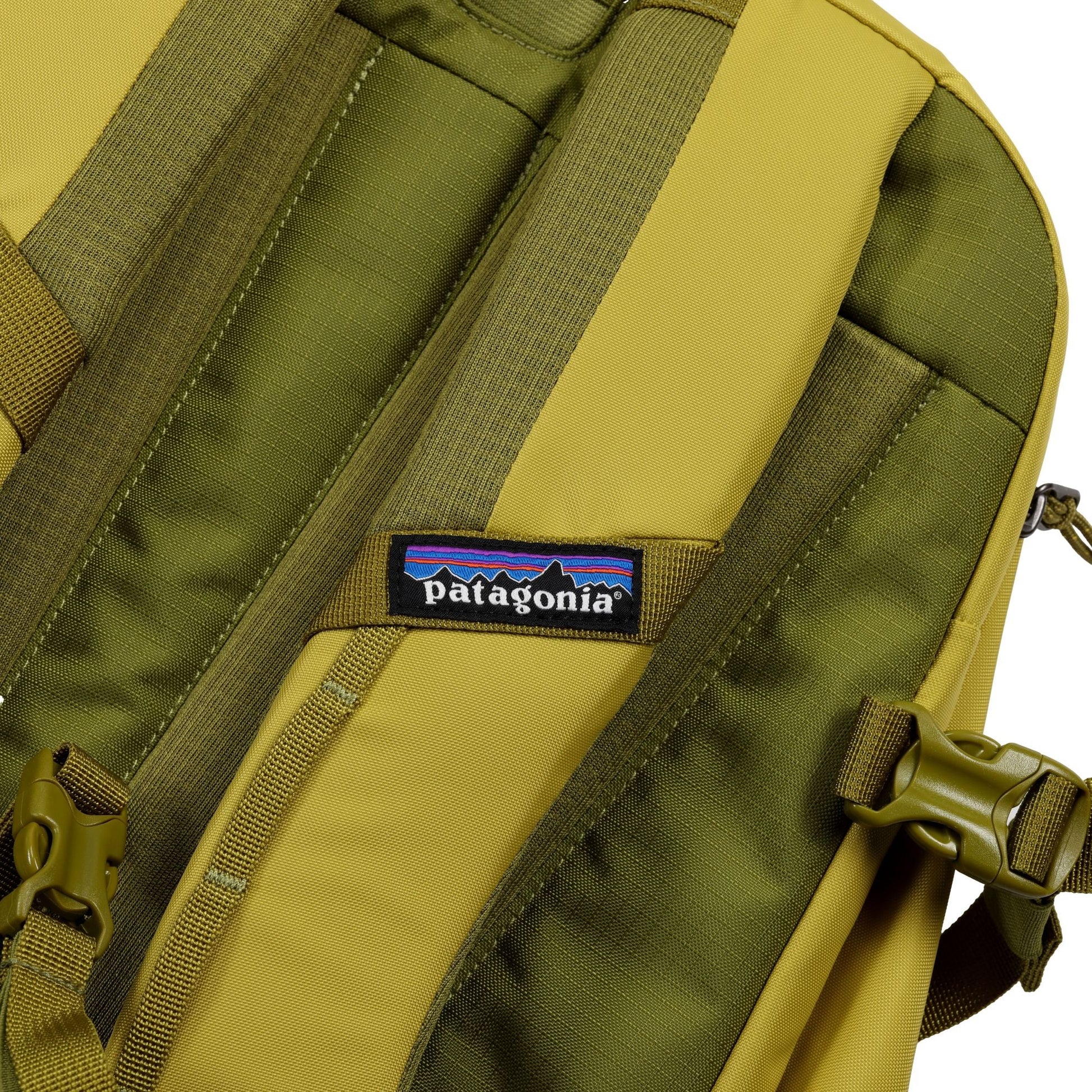 Close-up of a Patagonia Olive Refugio Day Pack 26L with visible logo patch, adjustable straps and buckles. Made from recycled polyester, this backpack fits a 26L capacity and is ideal for carrying your laptop.