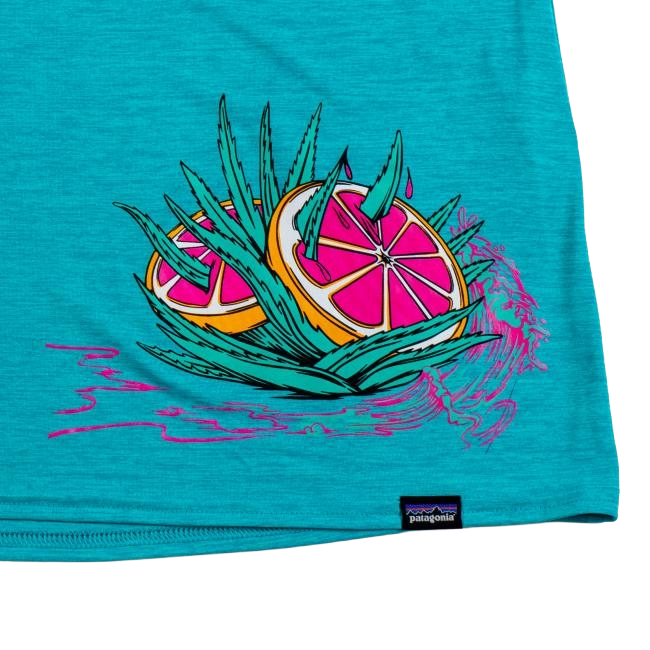 The Patagonia W Turquoise Runner Tank, made from recycled polyester, displays two pink grapefruit slices among green aloe with splashing pink liquid; a small Patagonia tag accents the bottom hem.
