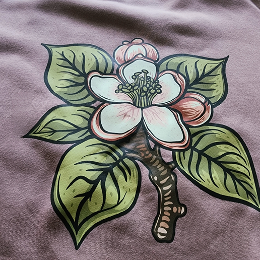 Close-up of back of crewneck featuring large image of pink flower and green leaves. 