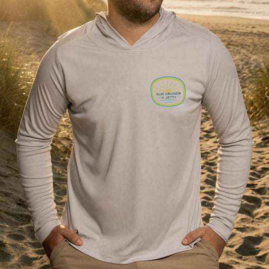 Person wearing a bone colored long-sleeve shirt with a logo on a beach