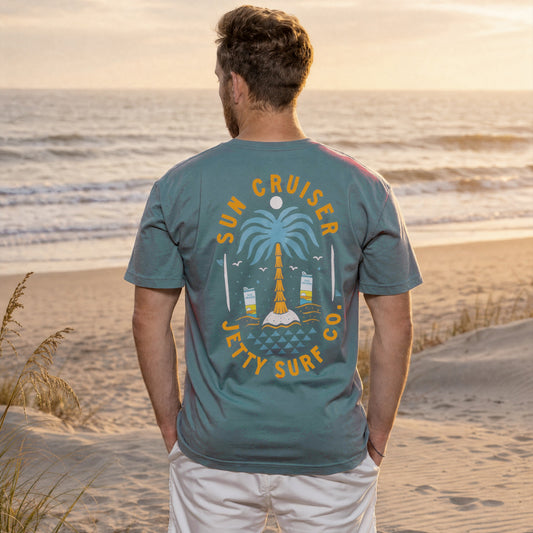 Blue short sleeve tee on person with large Sun Cruiser Jetty surf co palm tree graphic on back. 
