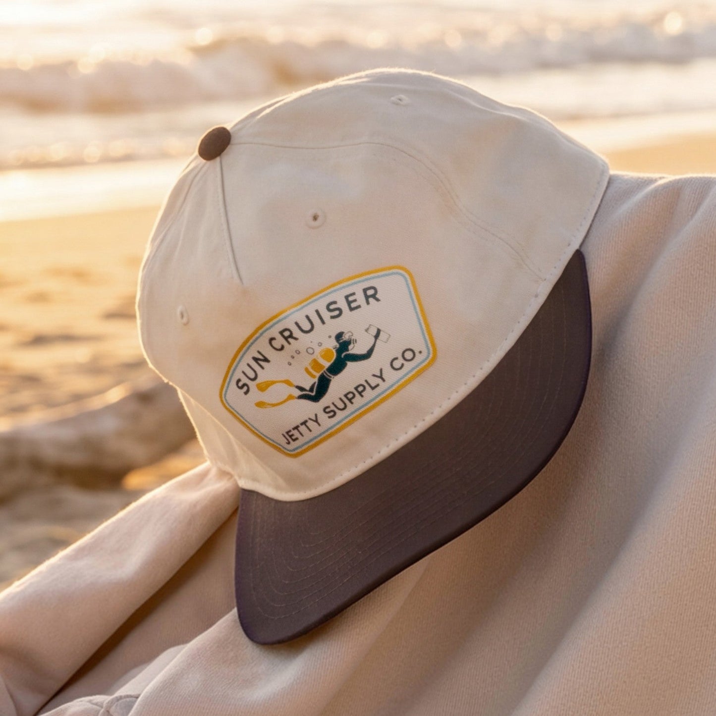 Beige cap with a logo on a chair on a beach at sunset