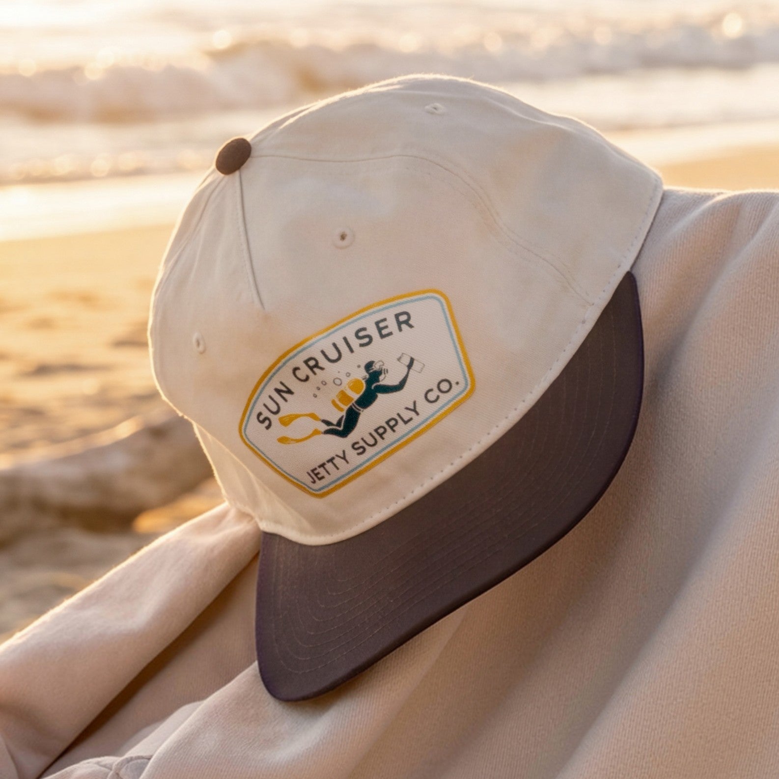Beige cap with a logo on a chair on a beach at sunset