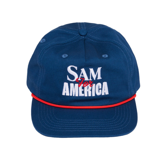 Navy blue Samuel Adams 250 rope baseball hat with white “SAM AMERICA” embroidered text, red script “for” detail, and red rope accent across the brim