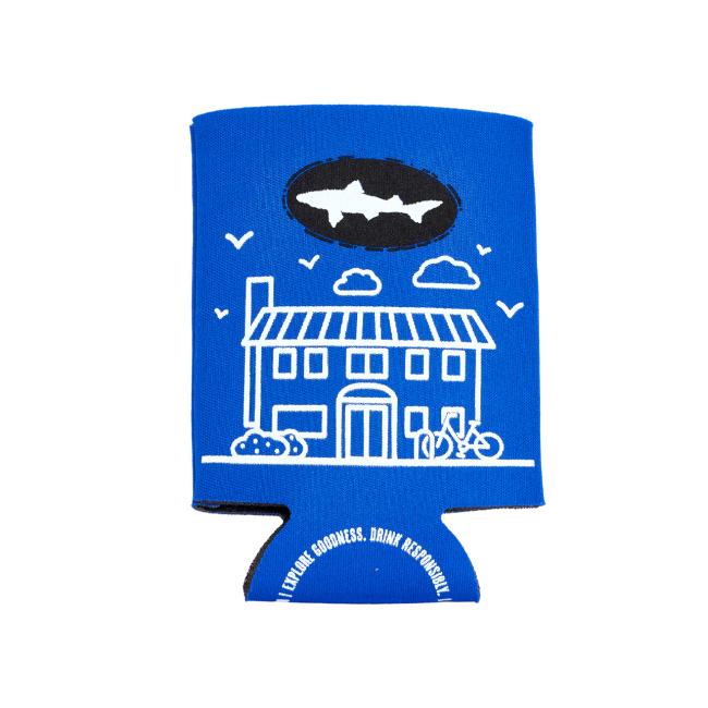 The INN 12oz Can Cooler by Grandstand Glassware & Apparel is a blue can cooler with a white line house, trees, birds, bike art, the Dogfish Head INN shark logo, and “LIFELONG GOODNESS. DRINK RESPONSIBLY.”—perfect for craft beer.