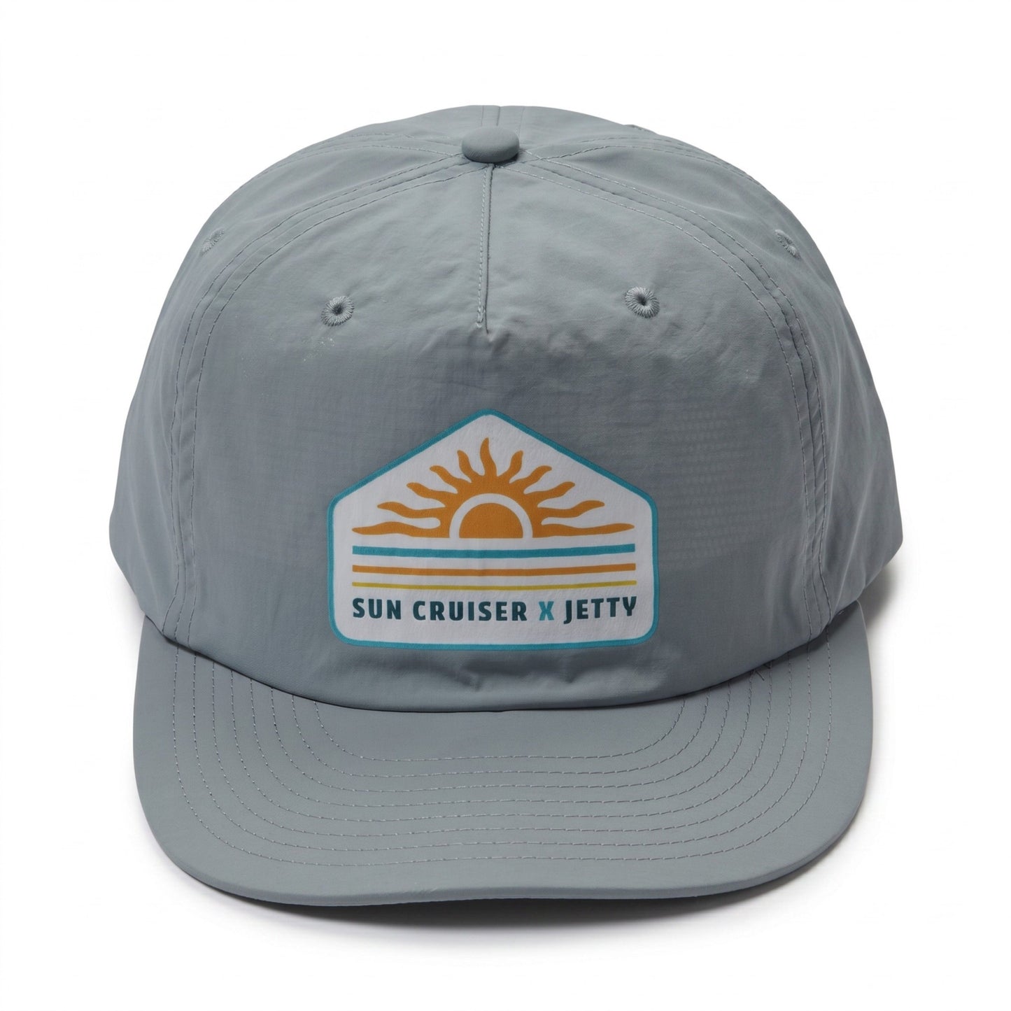 A light gray 5-panel baseball cap featuring a 'Sun Cruiser x Jetty' patch on the front, set against a plain white background.