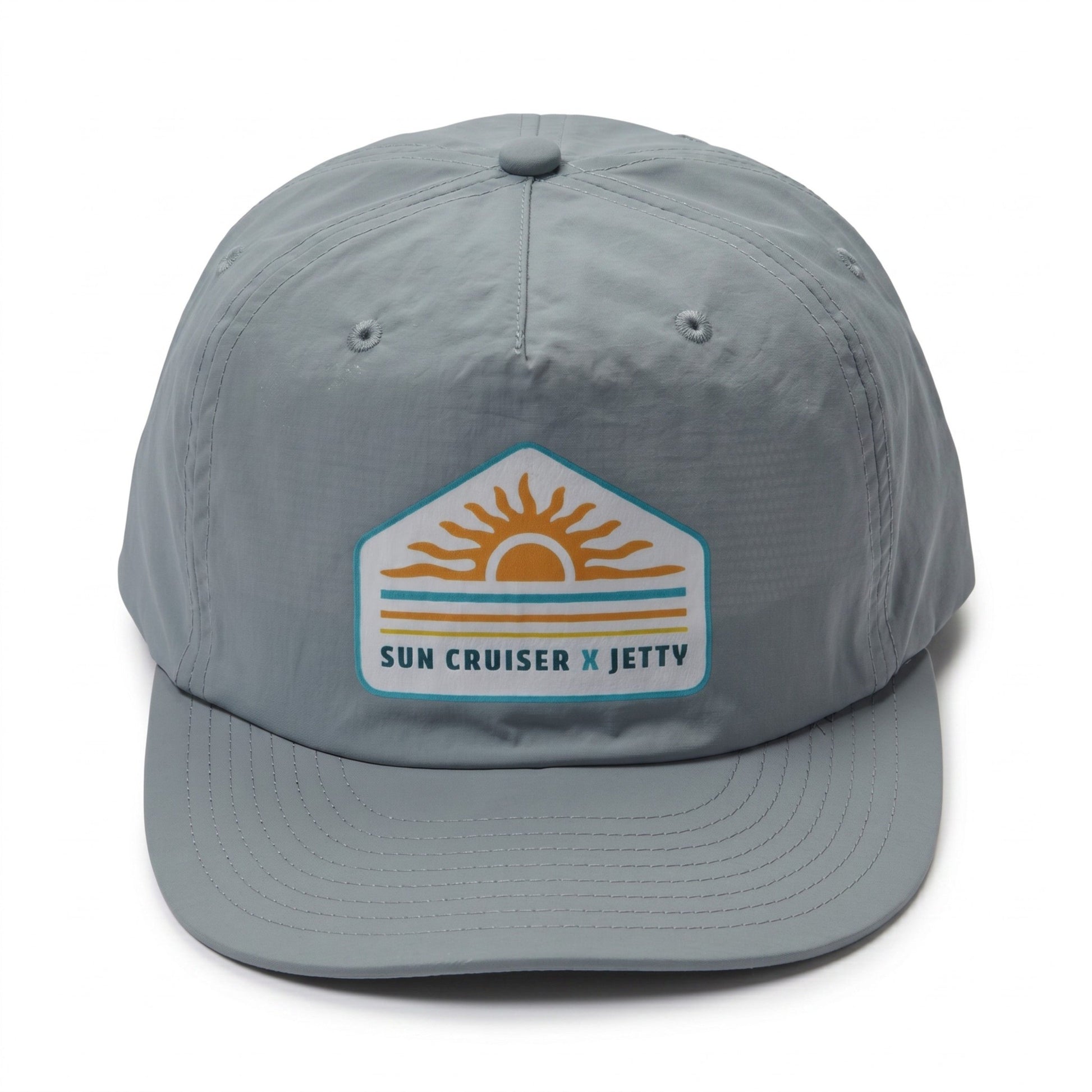 A light gray 5-panel baseball cap featuring a 'Sun Cruiser x Jetty' patch on the front, set against a plain white background.