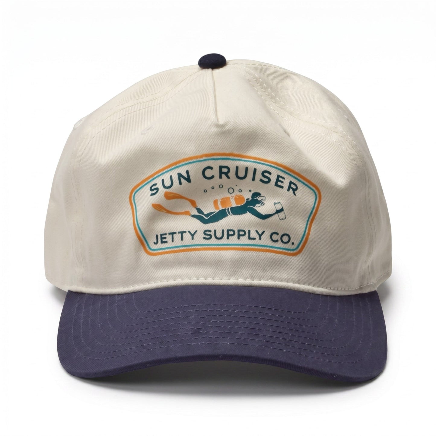 A baseball cap with an off-white crown and a dark navy blue curved brim. The front features a vintage-style embroidered patch that reads 'SUN CRUISER JETTY SUPPLY CO.