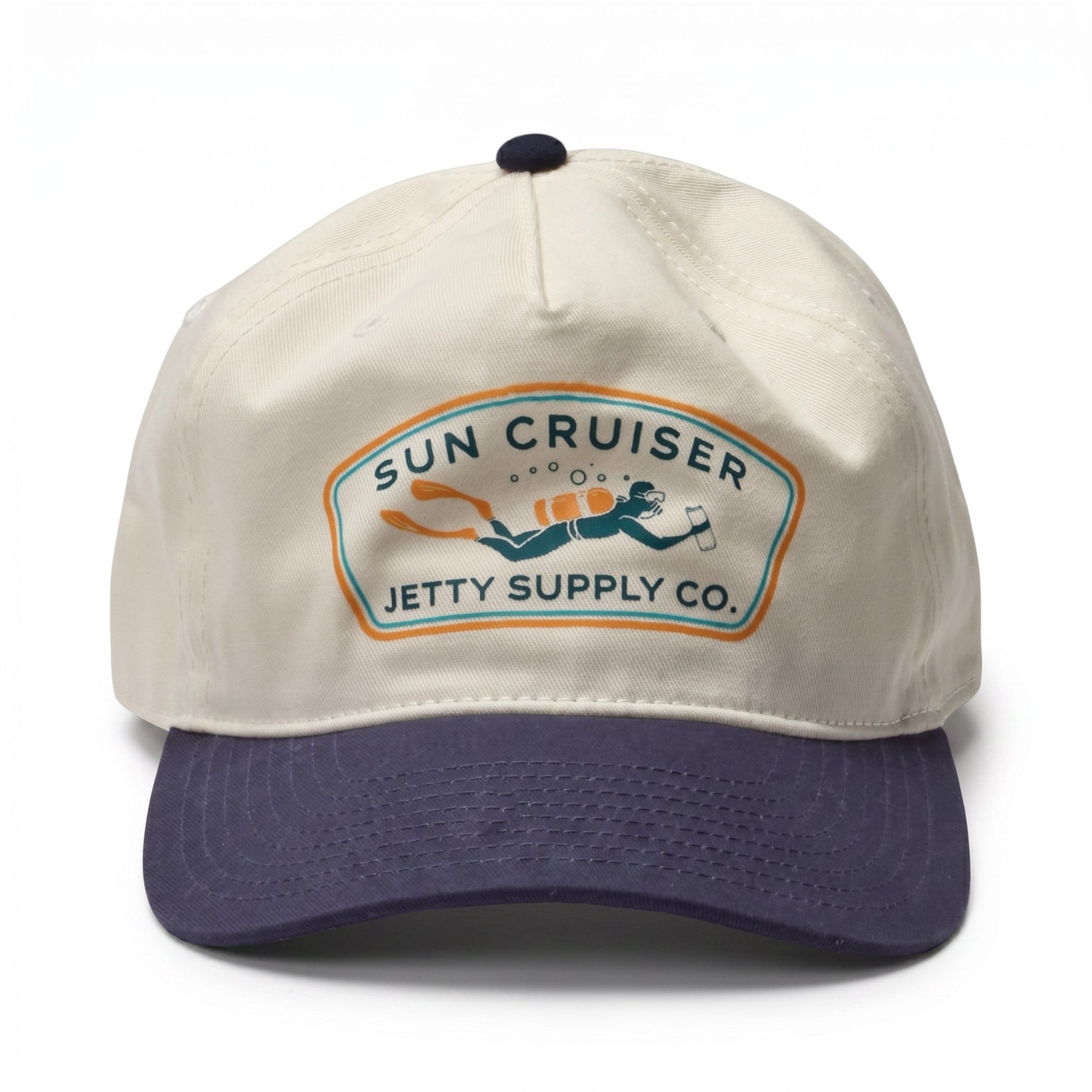 A baseball cap with an off-white crown and a dark navy blue curved brim. The front features a vintage-style embroidered patch that reads 'SUN CRUISER JETTY SUPPLY CO.