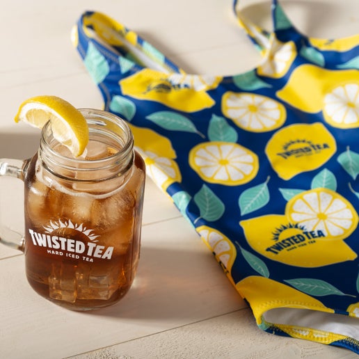 Glass mug with iced tea and lemon slice next to a Twisted Tea branded bag with lemon pattern