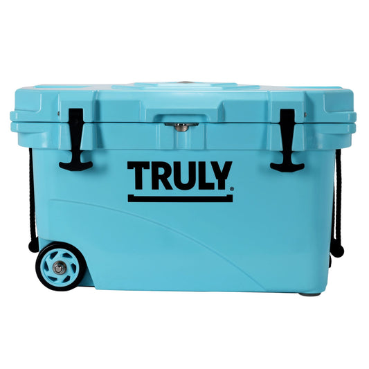 A light blue, possibly teal, portable cooler with "TRULY" in black text on the front. It has black latches, black rope handles, and wheels on one end.