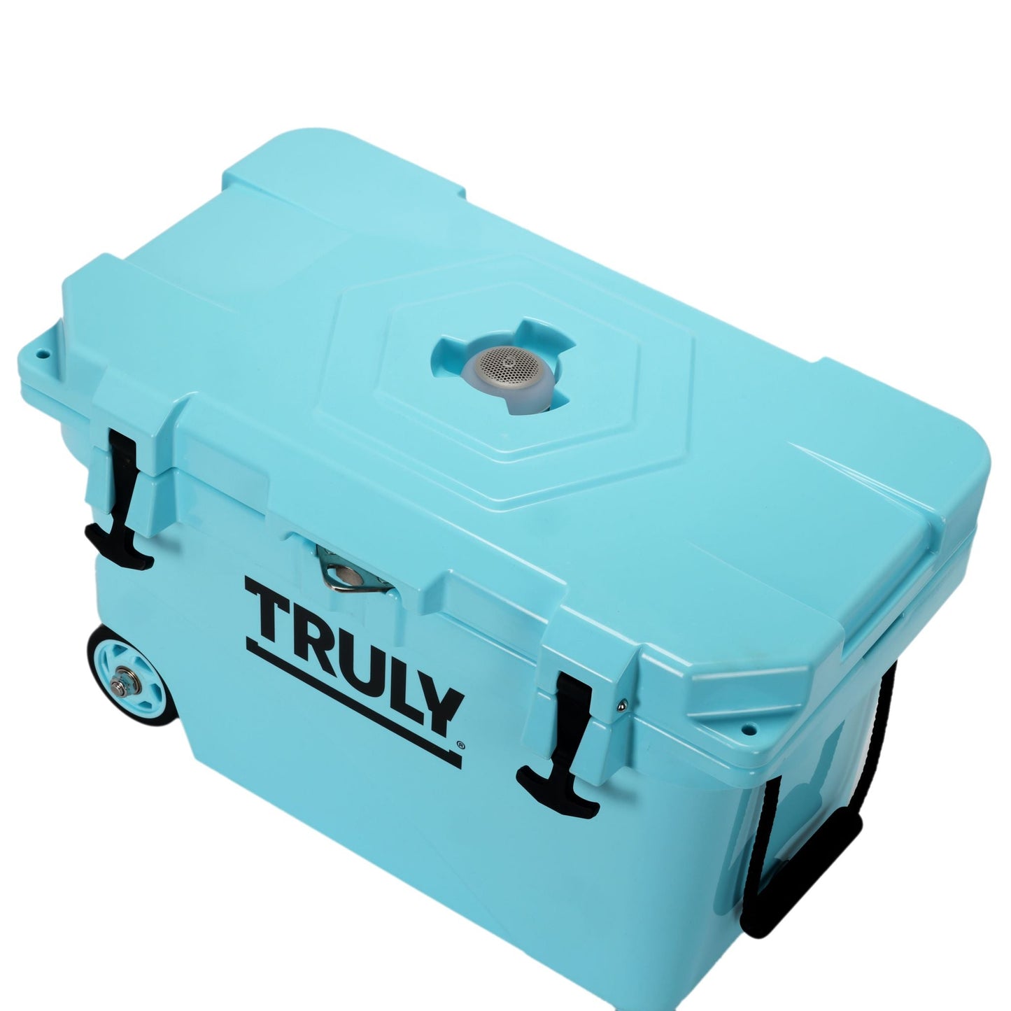 A light blue portable cooler with "TRULY" in black text on its side, seen from an elevated angle. It has black latches, a black rope handle, and a black wheel visible. On the top of the lid, there is a silver-colored speaker grille.