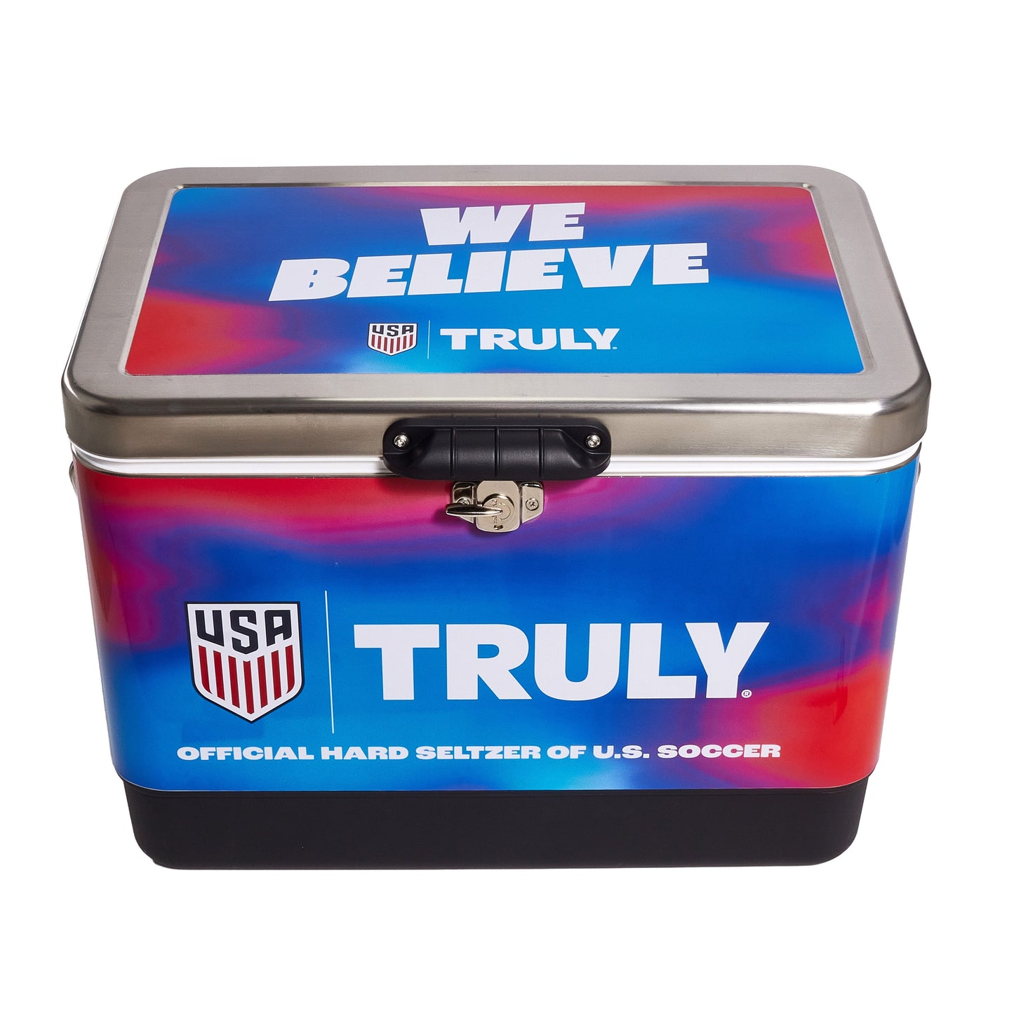Front view of the Truly USA metal cooler with a blue and red gradient design, displaying “WE BELIEVE” on the lid and large Truly branding with a shield‑style USA graphic on the front panel. The cooler includes a black latch closure and a durable black base.