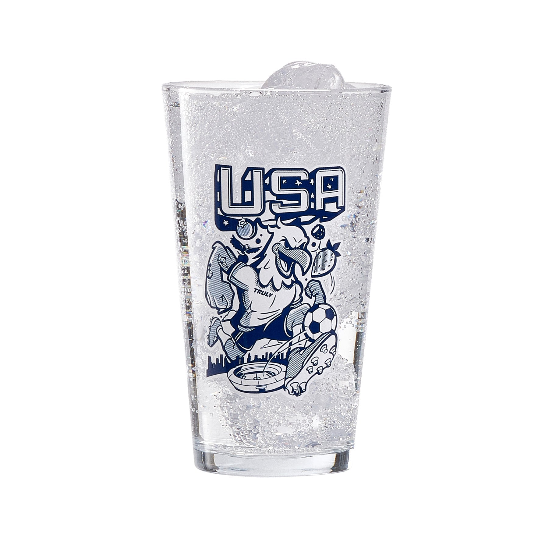Clear pint glass filled with ice and a fizzy beverage, displaying a navy illustration with large “USA” text above a stylized eagle character graphic and decorative fruit elements. The design sits prominently on the front of the glass, creating a bold, eye‑catching barware piece.