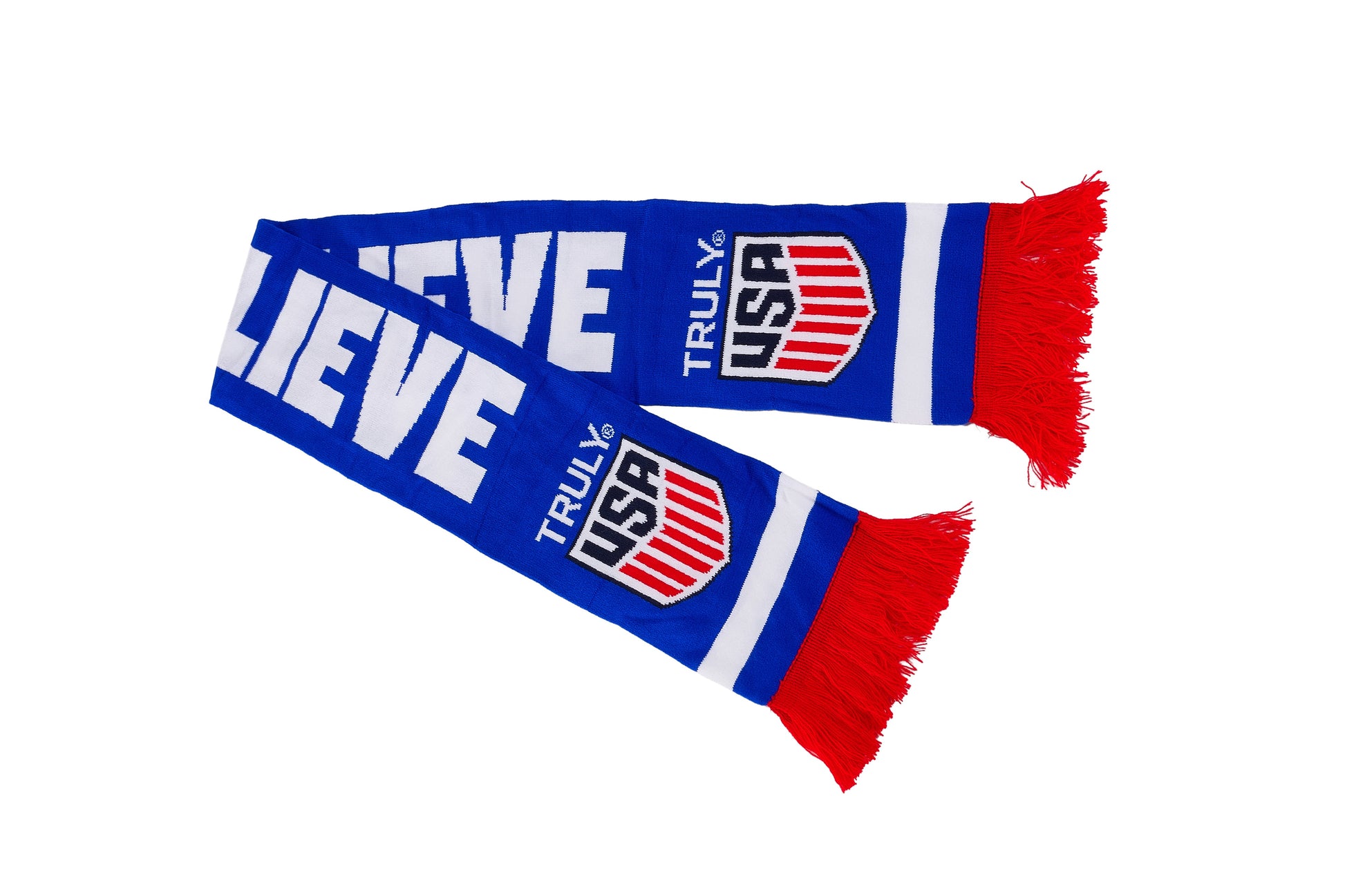 Blue knit Truly USA scarf displayed in a straight layout with bold white lettering, shield‑style Truly USA logos on both ends, red fringe detailing, and white horizontal accent stripes; colorful branded winter accessory.