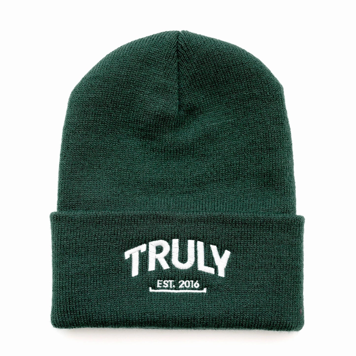 A dark green knit beanie with a folded cuff. "TRULY" is embroidered in white letters with "EST. 2016" underneath, also in white.