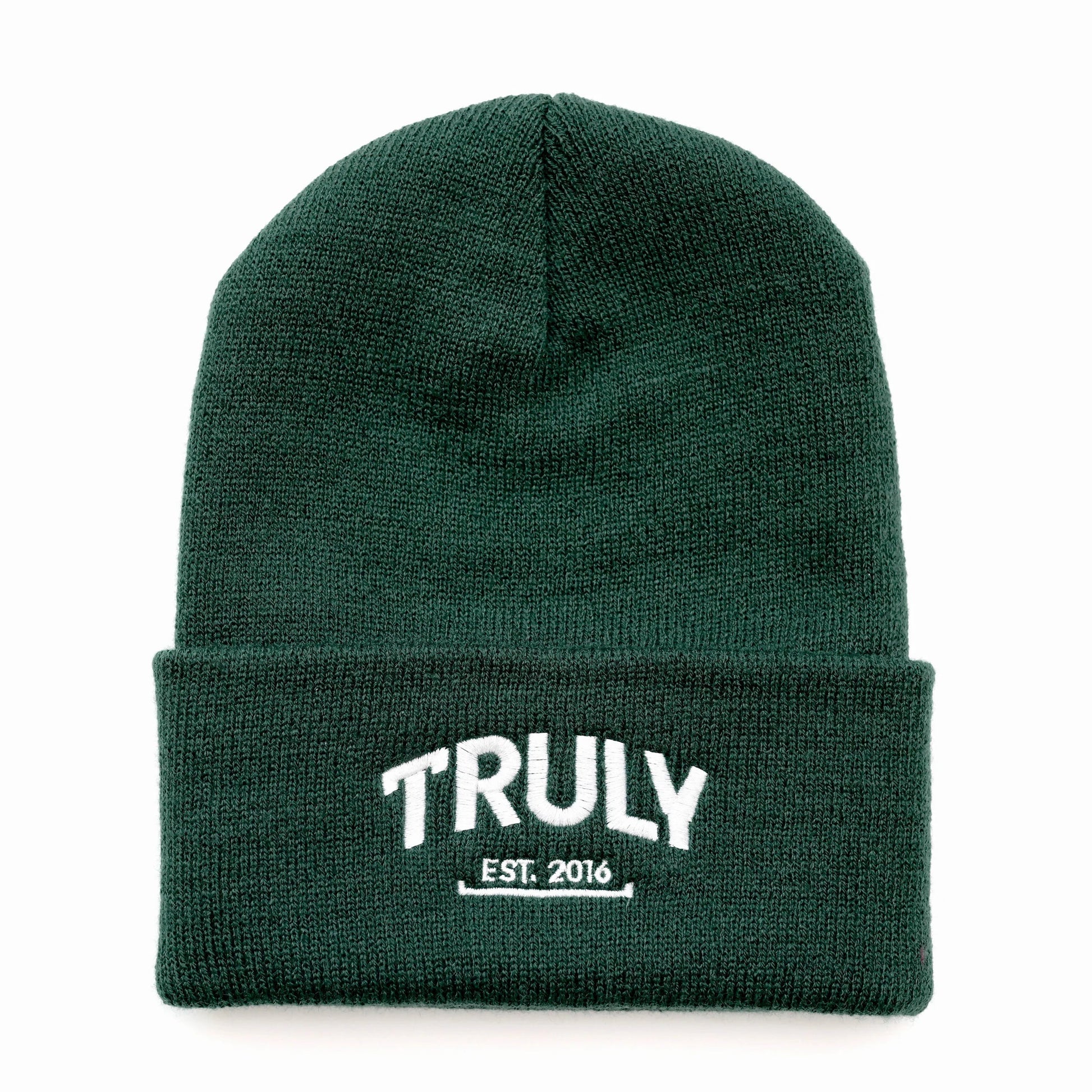 A dark green knit beanie with a folded cuff. "TRULY" is embroidered in white letters with "EST. 2016" underneath, also in white.