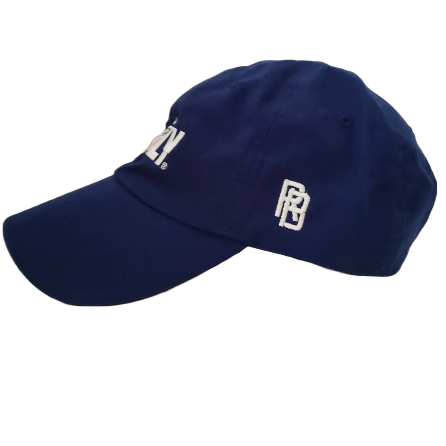 
A dark blue baseball cap, viewed from a side angle, showing the front and right side. There is a white logo or design embroidered on the front of the cap, which is partially visible. On the right side of the cap, a white stylized "RB" logo is embroidered.