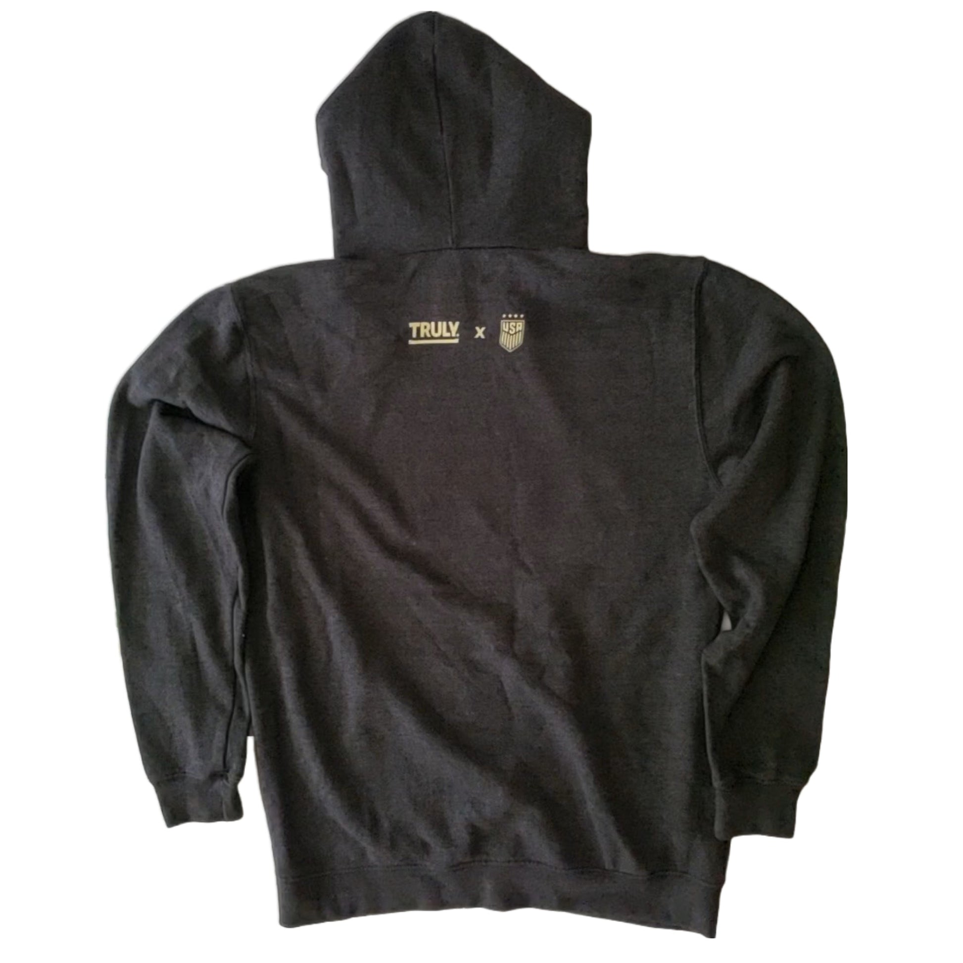 A dark gray hooded sweatshirt, viewed from the back. Near the top center of the back, there are two logos in a light, possibly gold or beige, color. On the left is the word "TRULY" with a horizontal line underneath it. To the right of "TRULY" is an "X" and then a emblem with "USA" and what appears to be a crest or shield design. The sweatshirt has long sleeves and a hood.