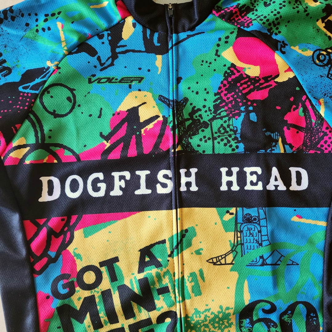 Close-up of Dogfish Head bike jersey showing colorful abstract graphics, logo text across chest, and moisture-wicking cycling fabric